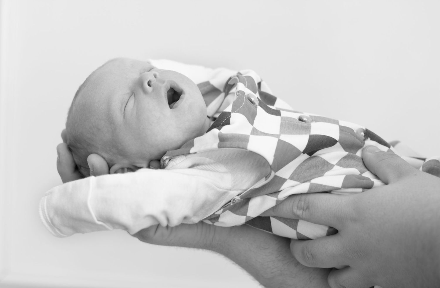 Baby stretching indoors in natural light during a professional studio portrait session by a expert Sioux Falls family photographer.