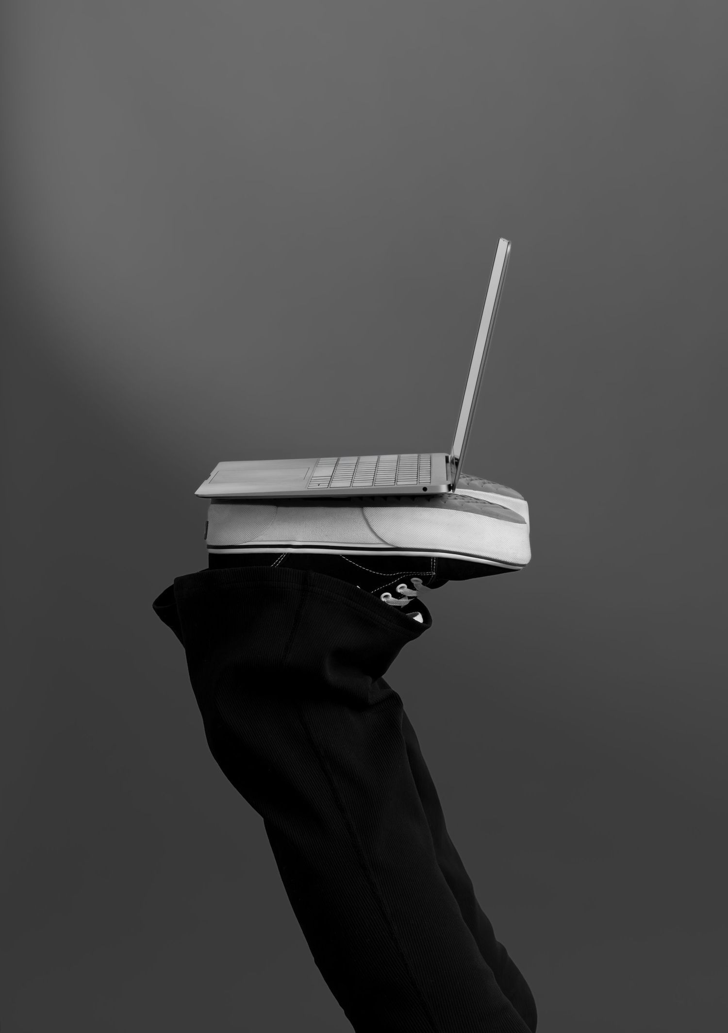 Unique black and white branding photo by Bree at Sixtwentytwo Images featuring a laptop balanced on sneakers. Conceptual personal branding.