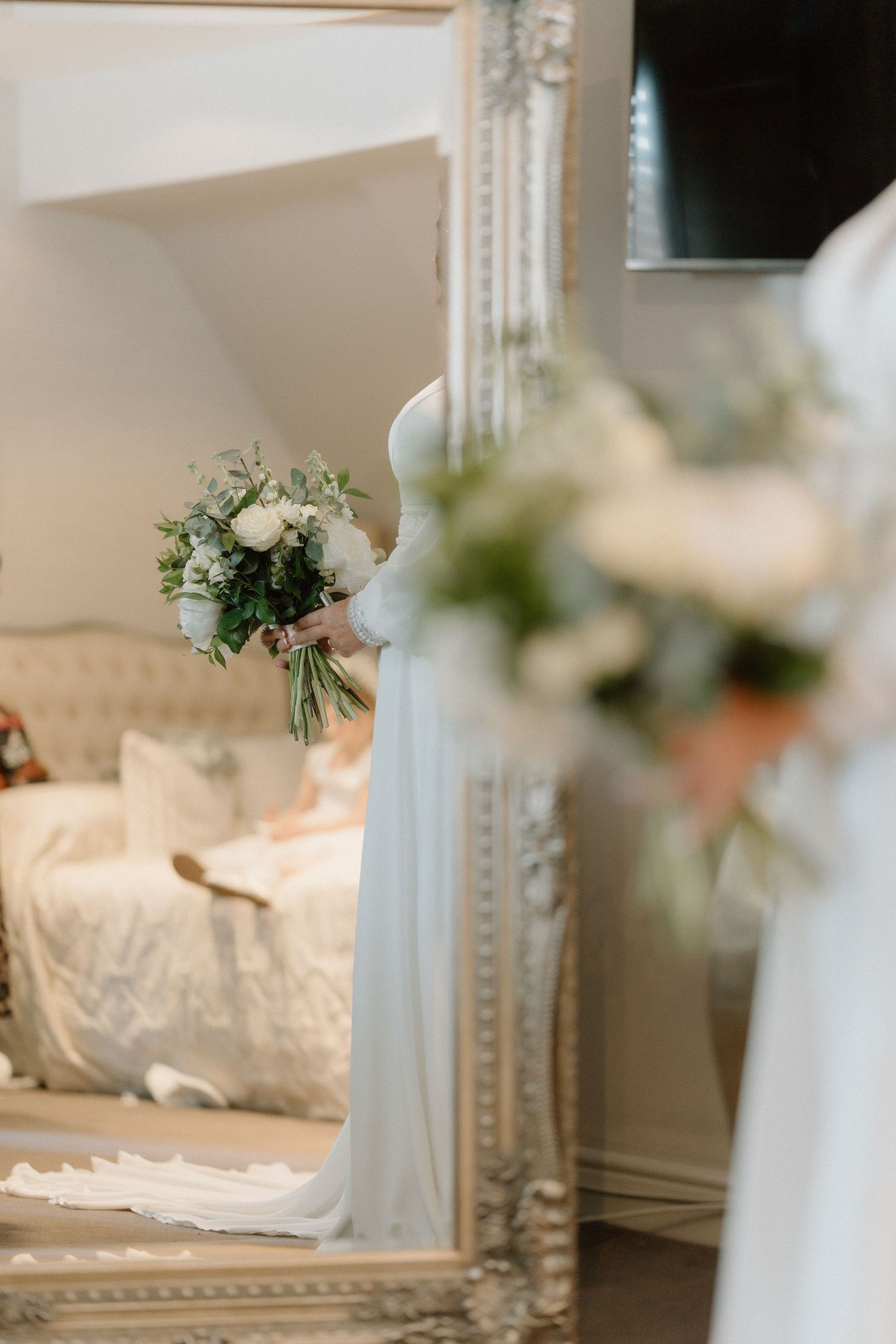 Delicate white bridal bouquet reflected in an ornate vintage mirror at Nuthurst Grange.