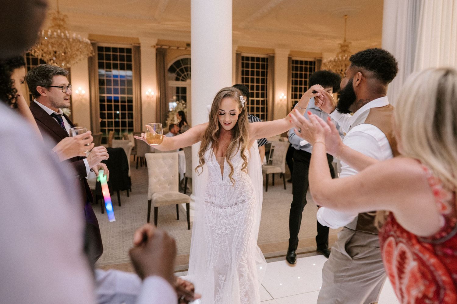 Wedding celebration dancing moment captured inside elegant white pillar venue.