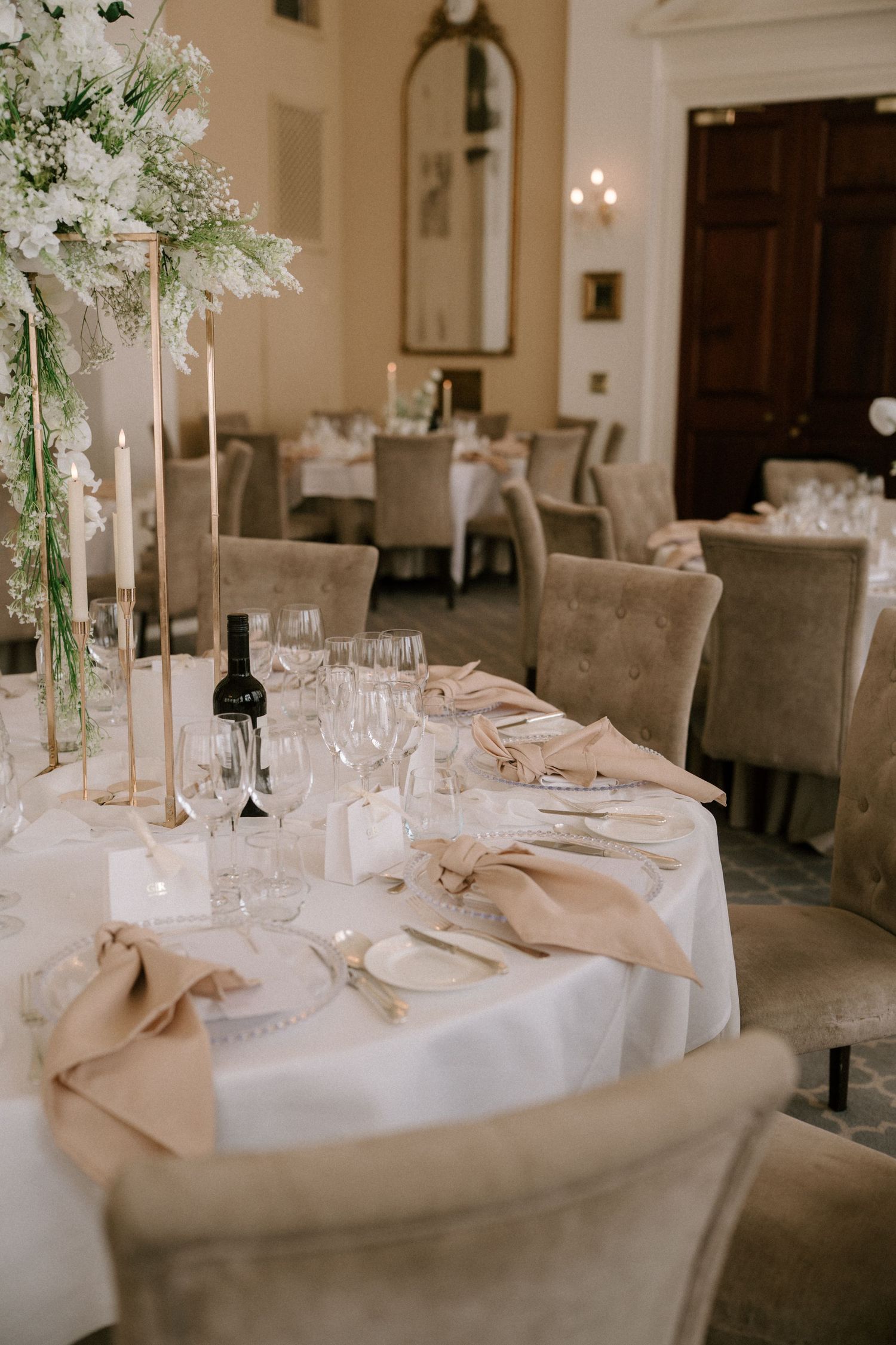 Elegant wedding reception table setting with tall floral centerpieces and white linens.