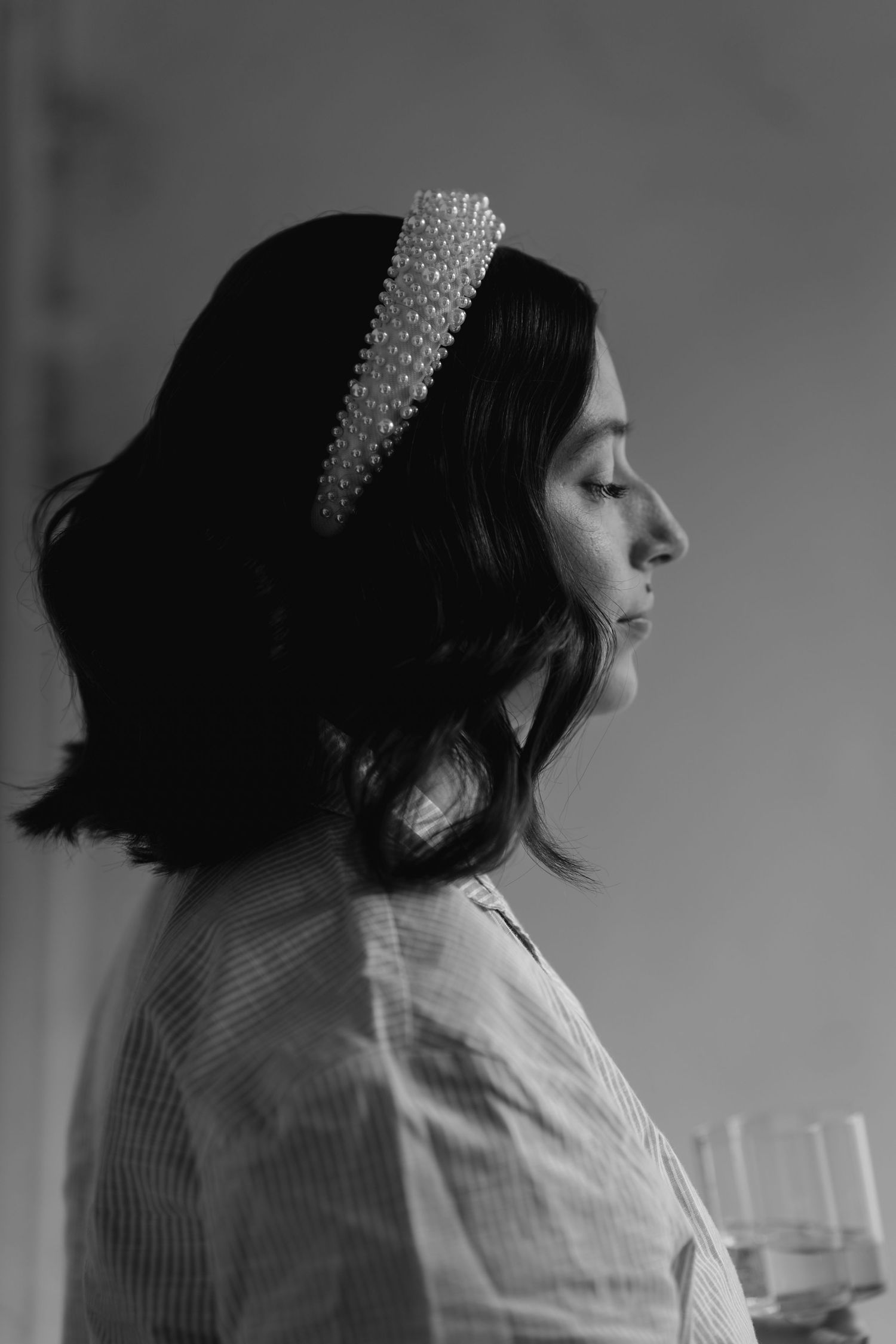 Black and white profile portrait of a bride wearing a pearl headband with dark wavy hair.