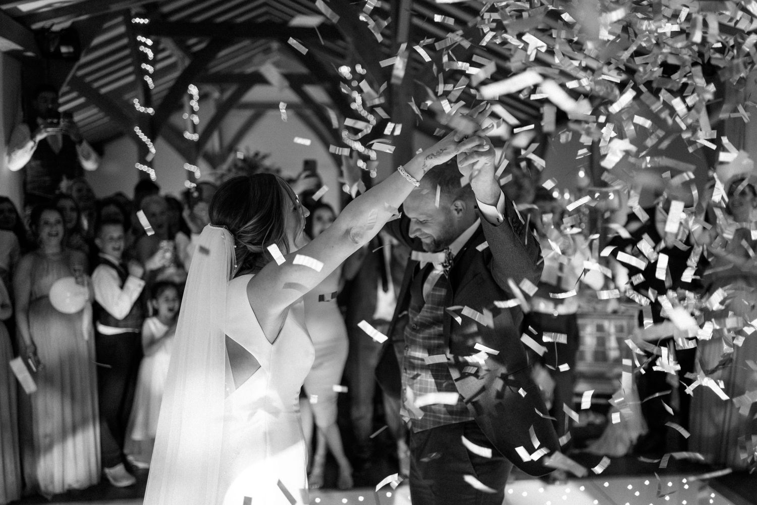 A bride and groom celebrate under a shower of white confetti at Dodford Manor.