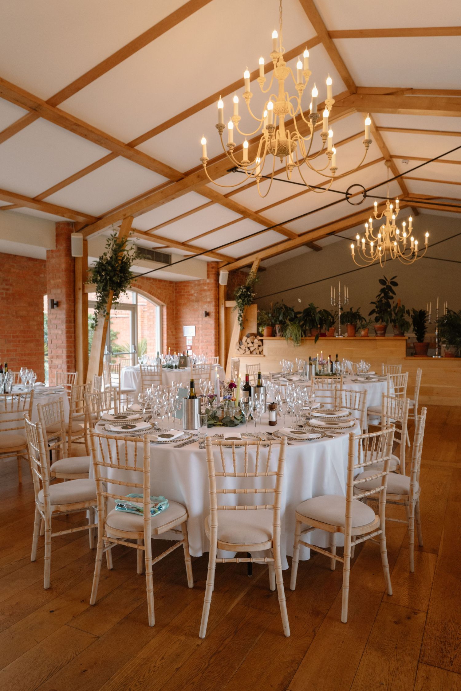 Elegant wedding reception hall with round tables, chiavari chairs, and gold chandelier lighting.