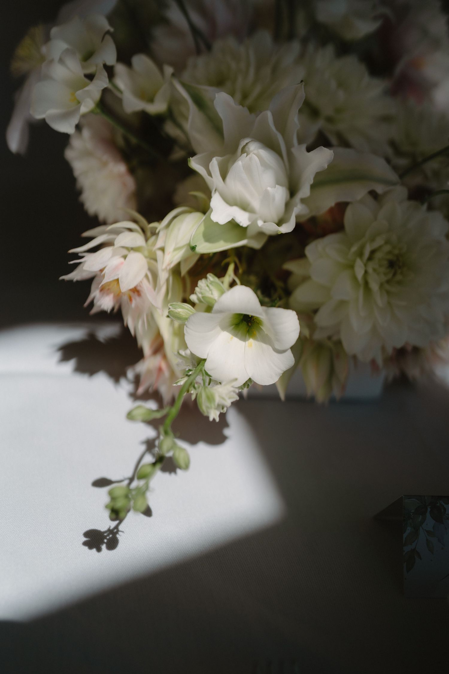 Elegant white and blush floral arrangement with dahlias and delicate blooms in soft natural light.