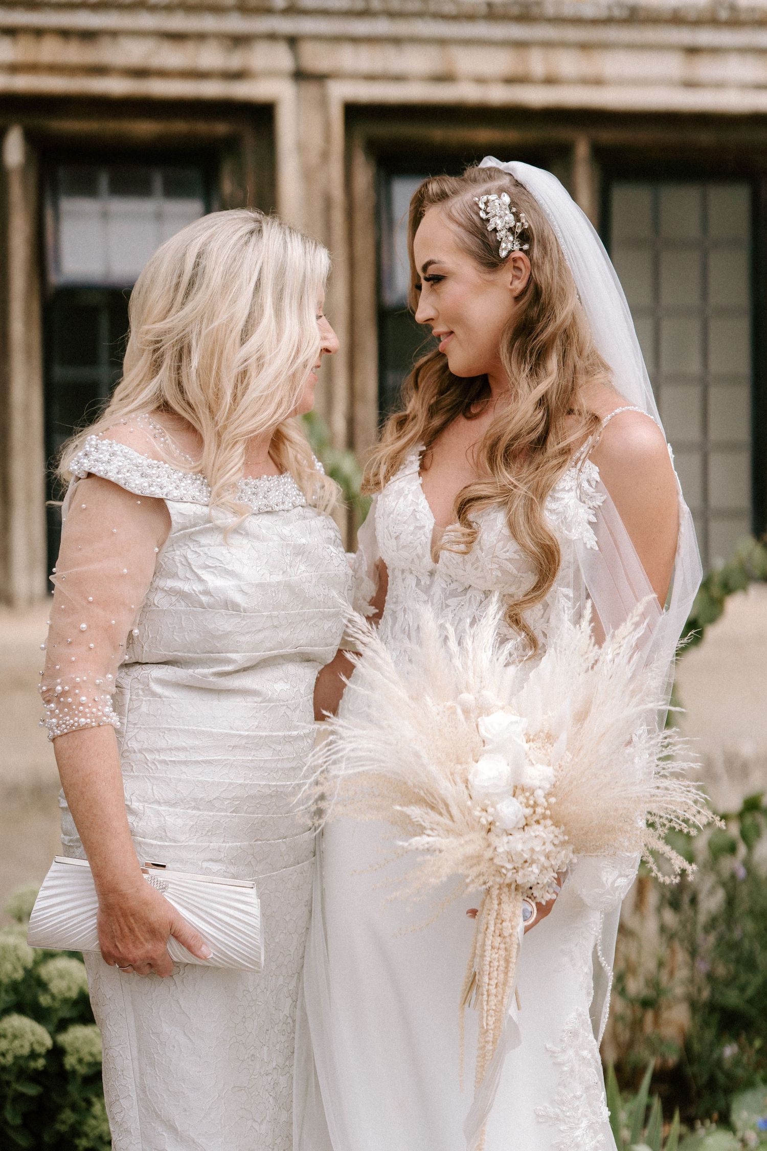 Candid moments captured of wedding party members in white dresses with pampas grass bouquets.