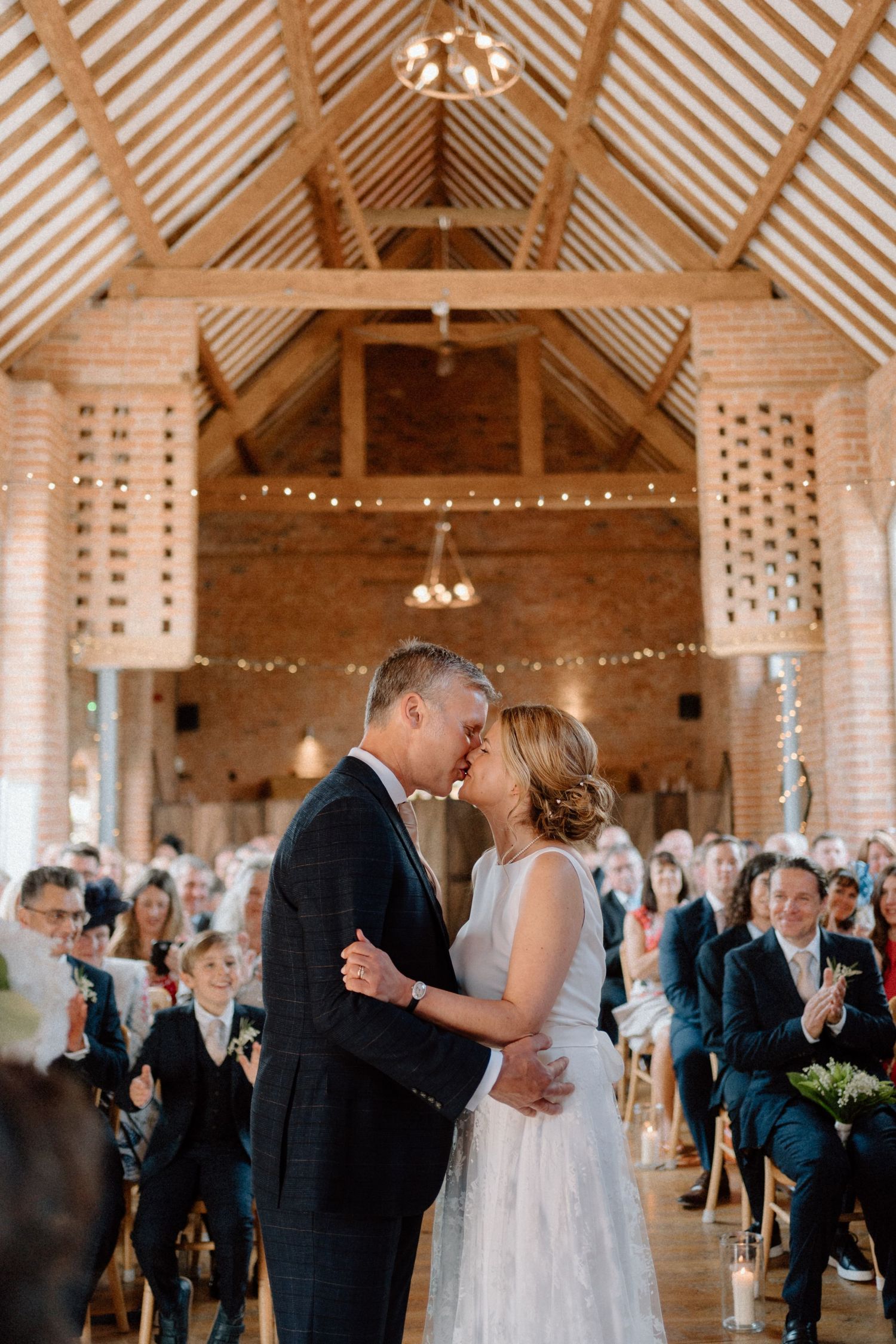 A romantic first dance in a rustic wooden barn venue decorated with string lights and chandeliers at Swallows Nest Barn.