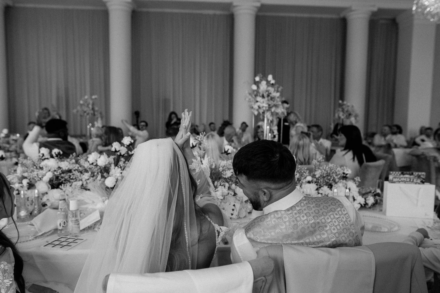 An elegant wedding reception setup with white columns and floral centerpieces in a formal dining room.