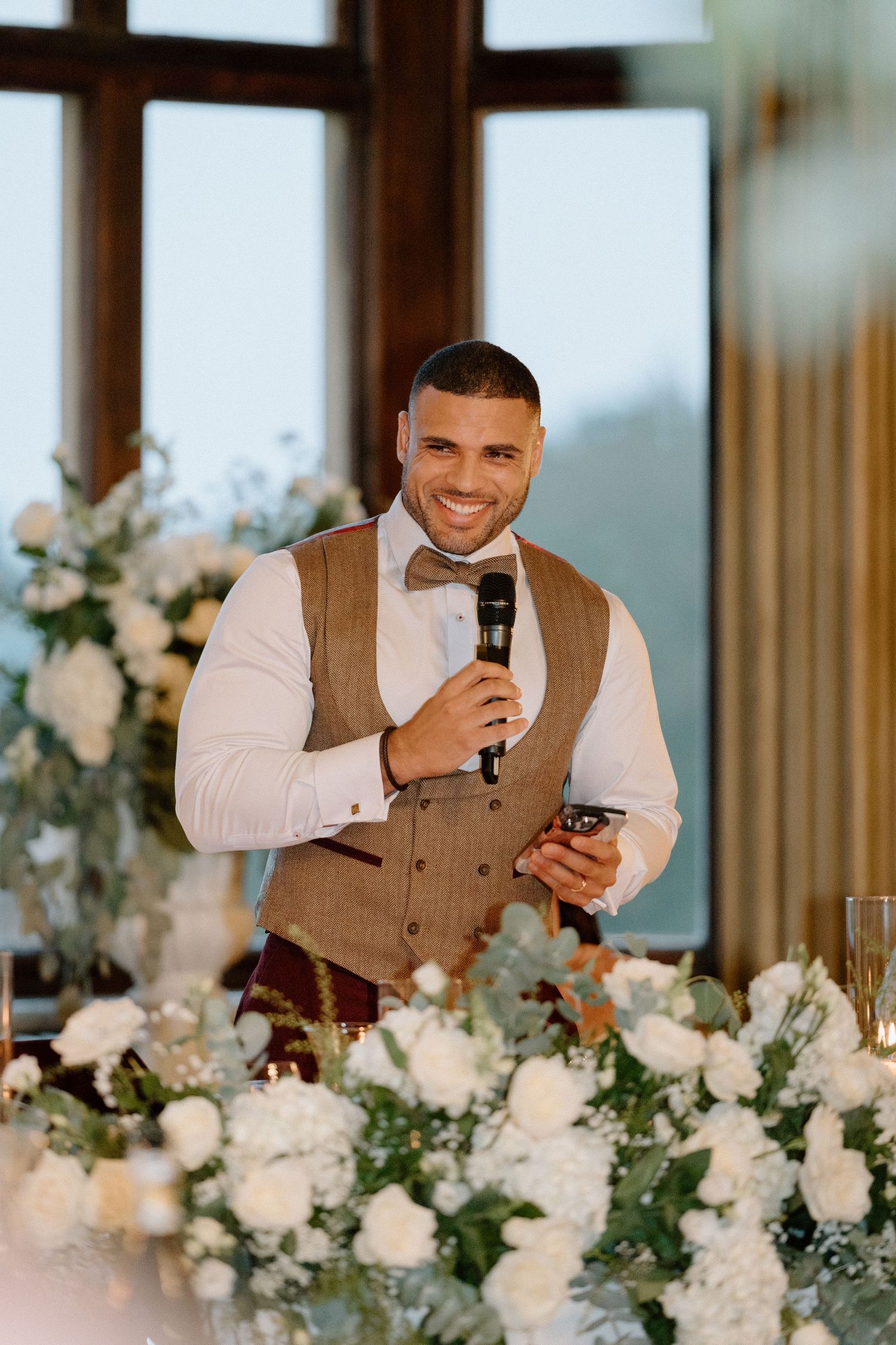 A wedding toast speech at an elegant reception with white floral centrepieces at Harlaxton Manor.
