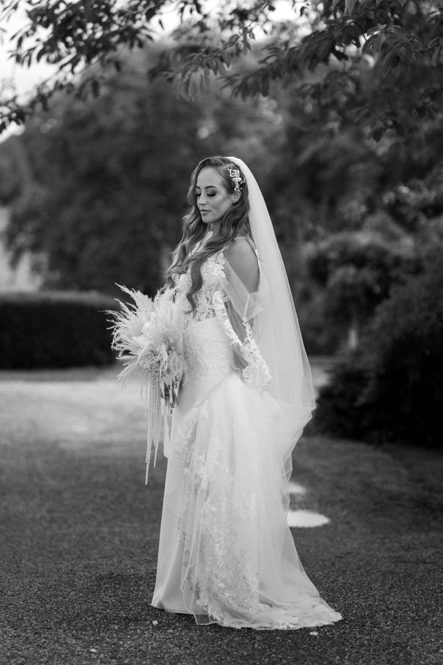 Artistic black and white portrait series of a bride with flowing veil in an outdoor garden setting.