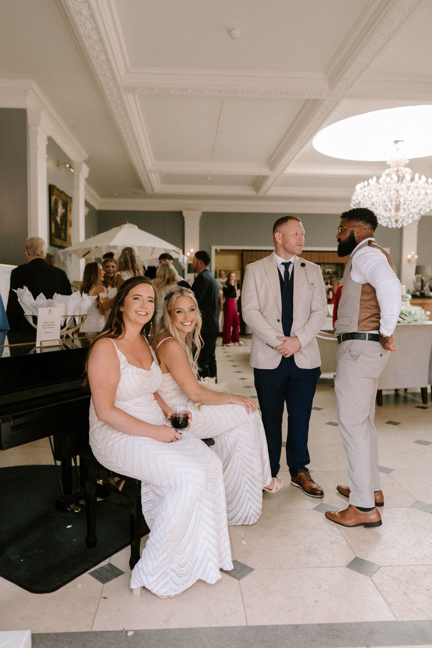 Wedding reception guests enjoying themselves on a white dance floor under crystal chandeliers.