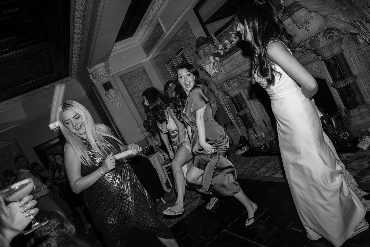 People dancing and celebrating at a lively wedding reception party in an elegant venue at Ettington Park Hotel.