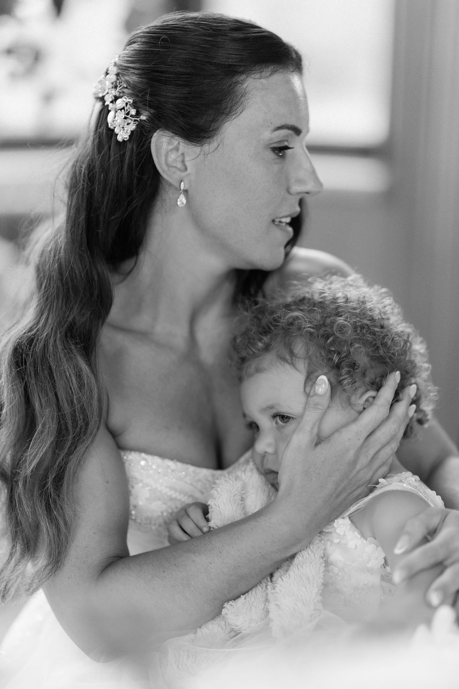 An intimate black and white portrait capturing a tender moment between bride and baby at Harlaxton Manor.