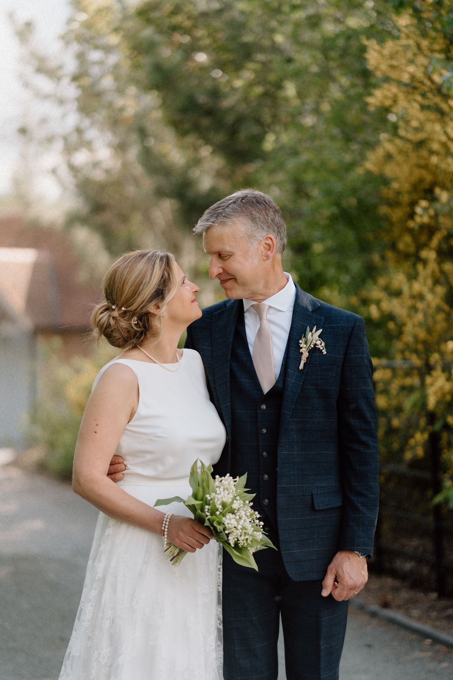 A couple shares a sweet moment during their outdoor wedding with golden autumn foliage in the background at Swallows Nest Barn.