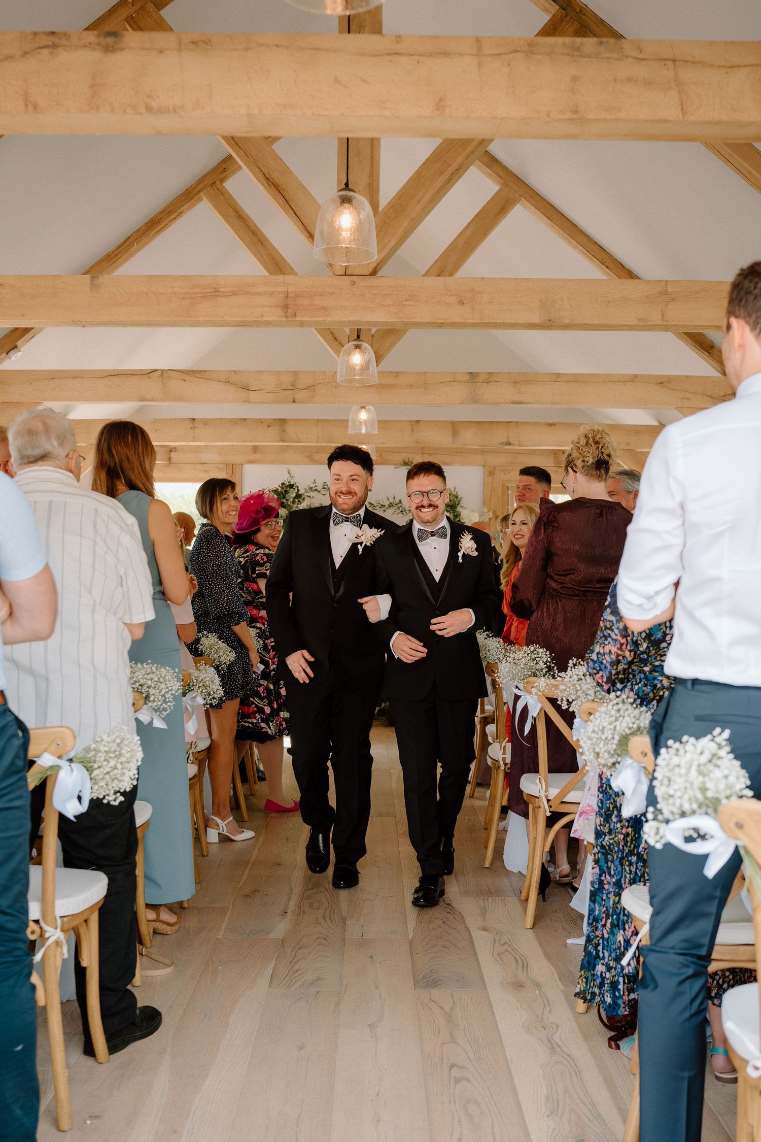 A joyful wedding ceremony in a rustic barn venue with wooden beams and natural lighting at The Manor House at Quorn.
