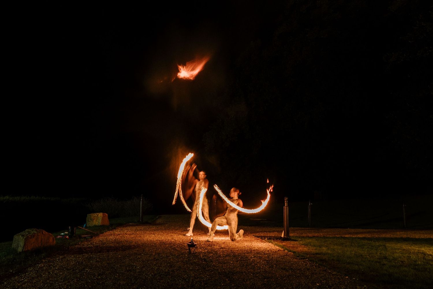 Long exposure night shot of fire dancers performing at outdoor wedding reception.