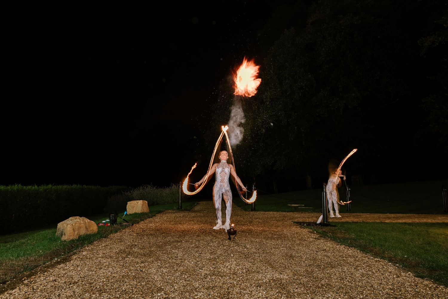 Fire performers create dramatic entertainment at an outdoor nighttime wedding.