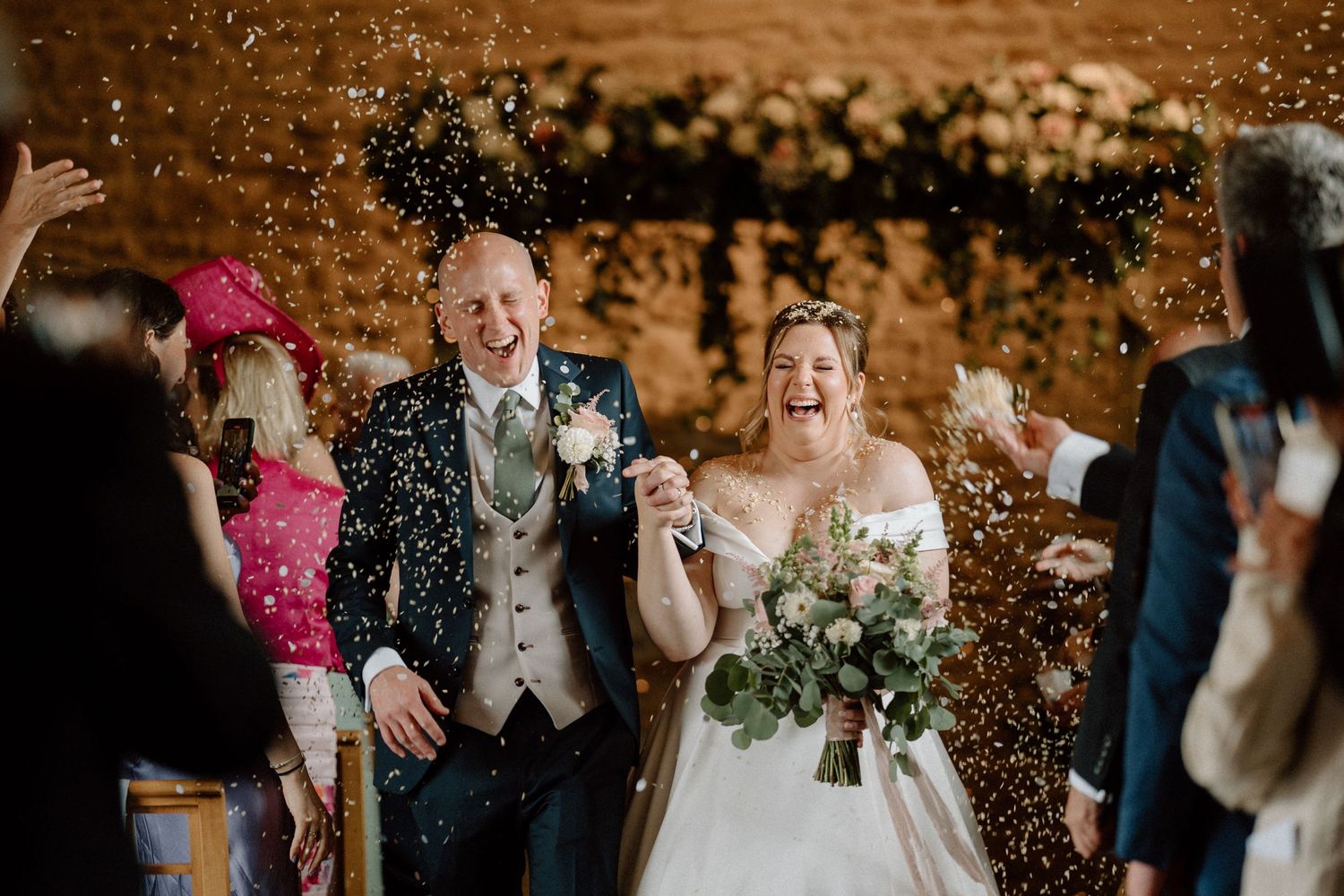 Joyful wedding exit with confetti shower in rustic venue at Dodford Manor.