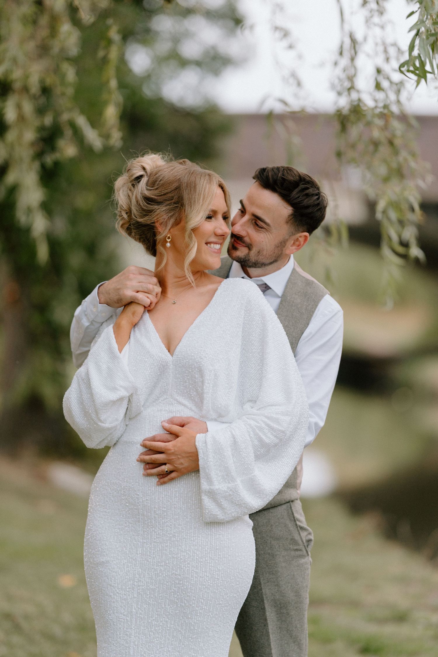A tender moment shared between newlyweds under weeping willow branches in Solihull.