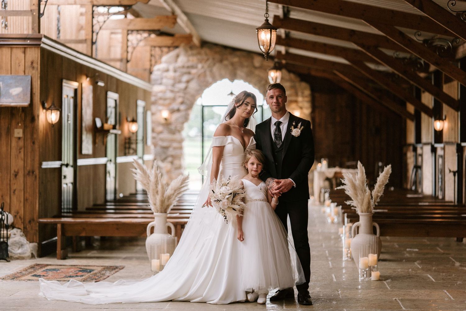 Wedding couple poses together in rustic indoor venue with wooden beams and stone walls.