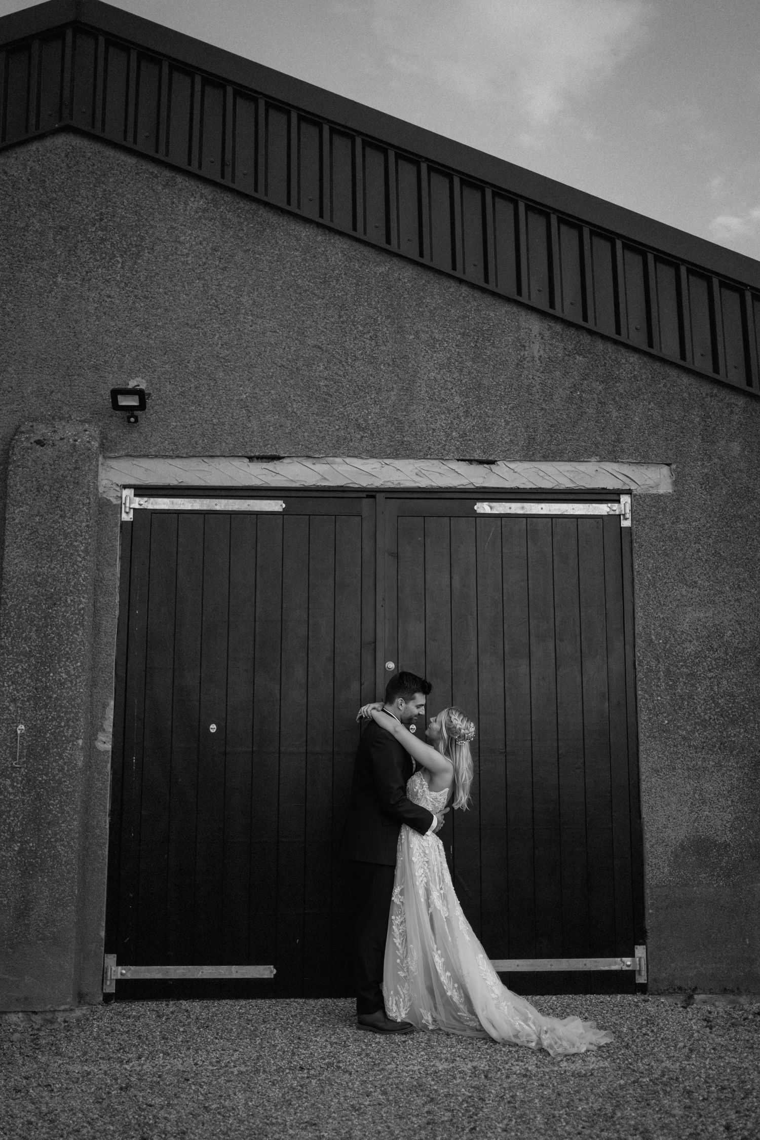 A romantic black and white wedding photograph in front of a rustic barn door at Milling Barn.