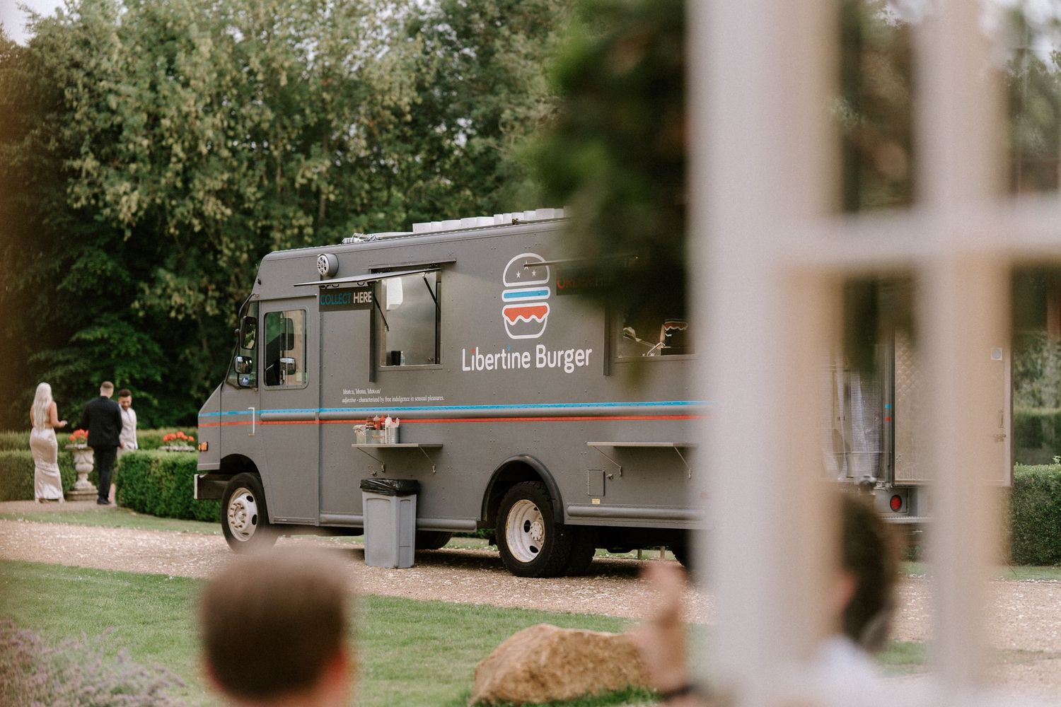 A vintage-style food truck parked on the grounds of a wedding venue.