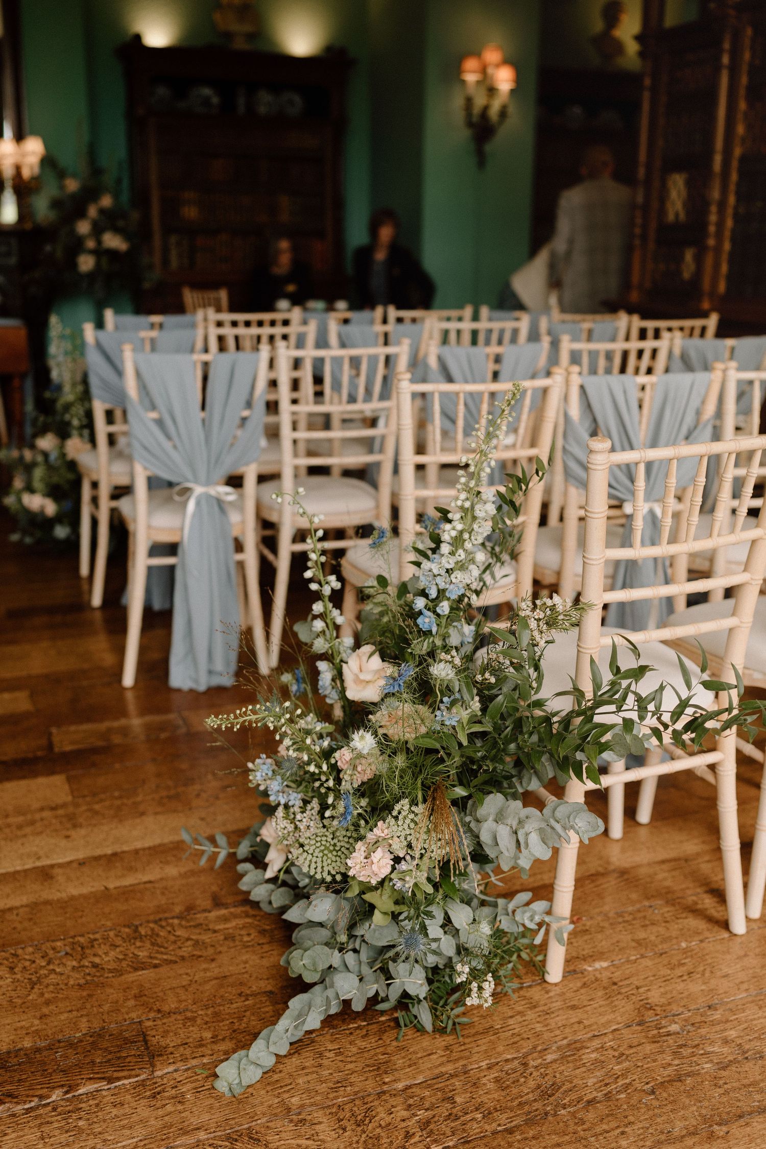 Elegant wedding ceremony setup with white chairs decorated with blue sashes and floral arrangements at Prestwold Hall.