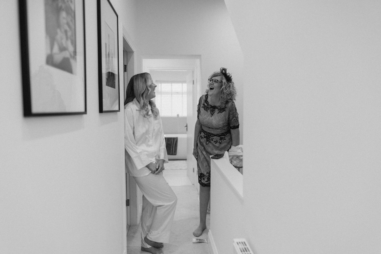 Mother and daughter share a candid moment in a hallway during wedding day preparations.