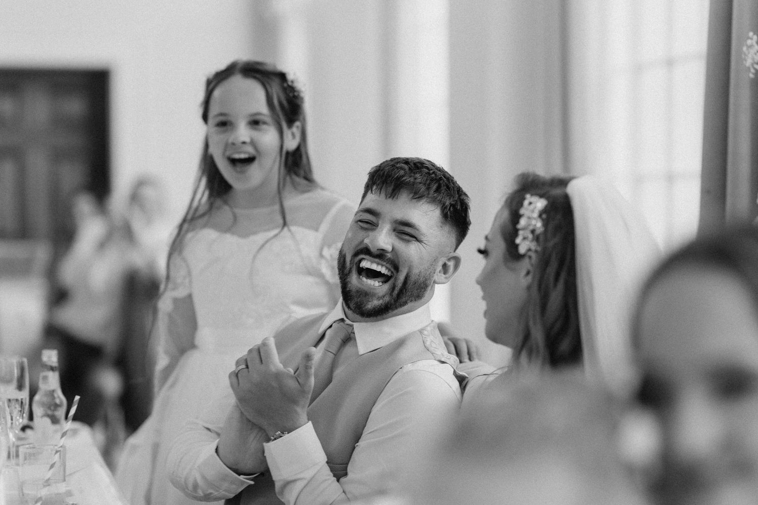 Black and white candid moment during wedding reception speeches.