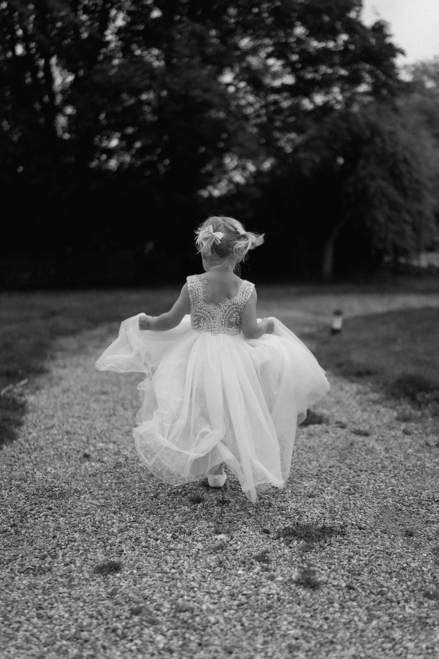 Black and white photo of young girl twirling in white dress outdoors in Warwickshire.