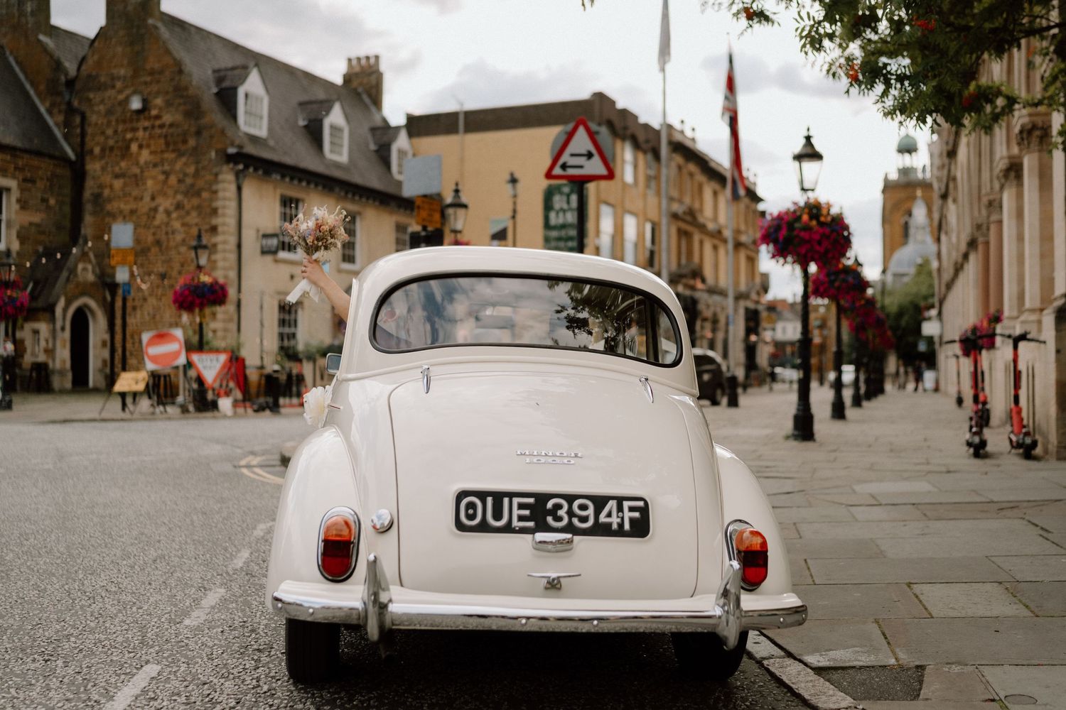 A classic white Morris Minor vintage car parked on a charming British town street in Northampton.