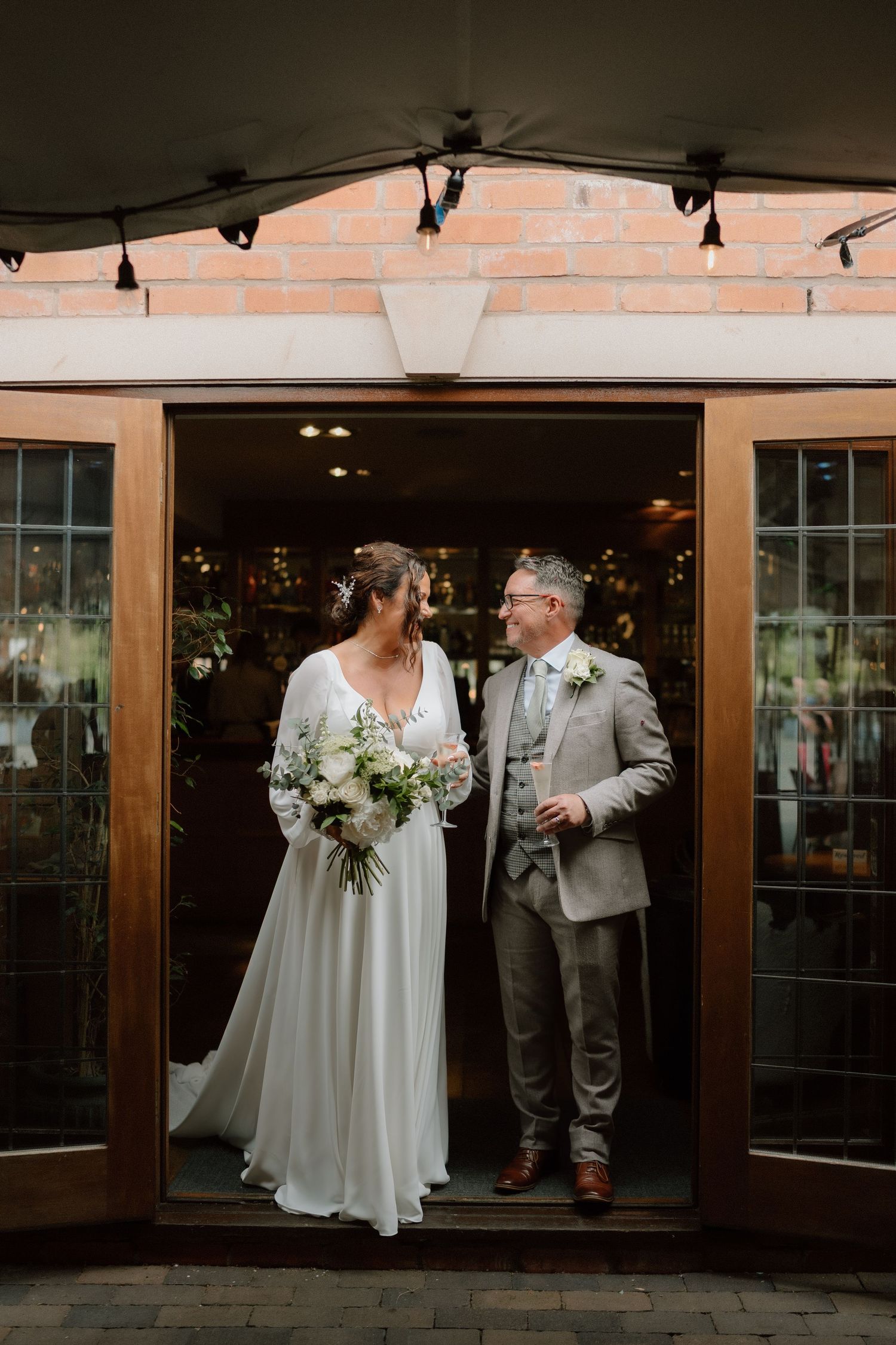 Couple stands in wooden doorway during wedding celebration at Nuthurst Grange.
