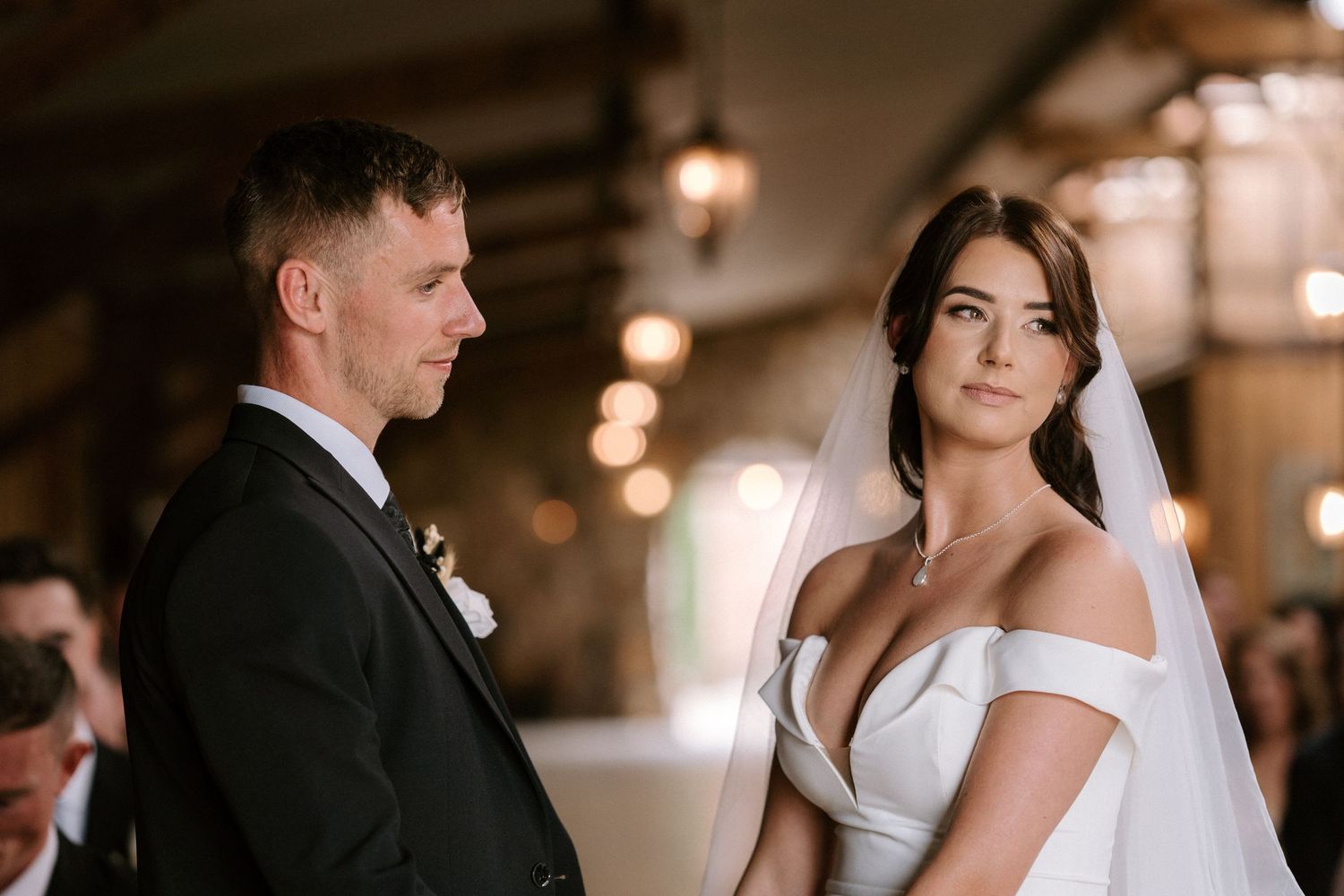 A couple exchanges vows during their wedding ceremony in a warmly lit indoor venue.