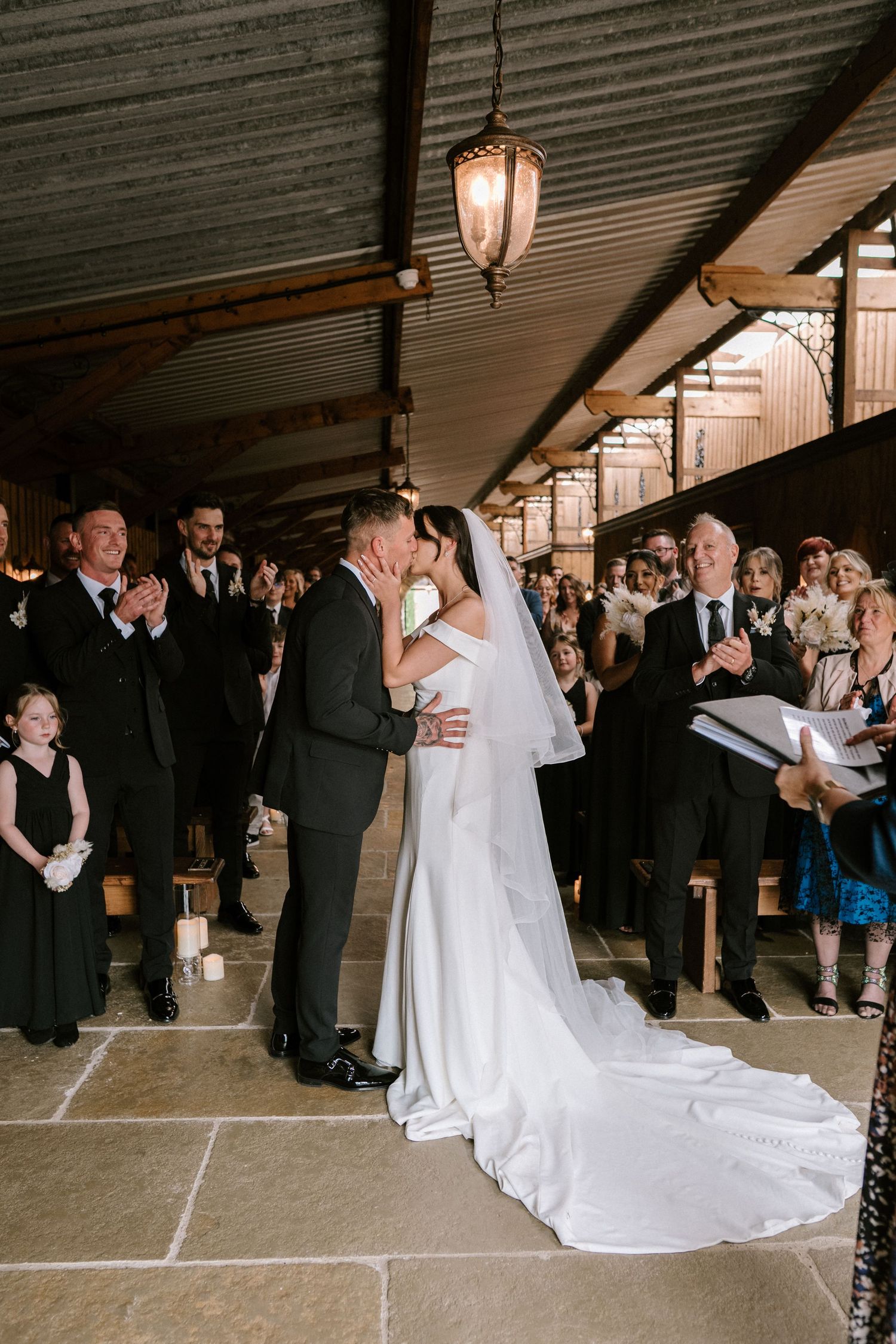 Guests watch a wedding ceremony in an elegant indoor venue with pendant lighting.