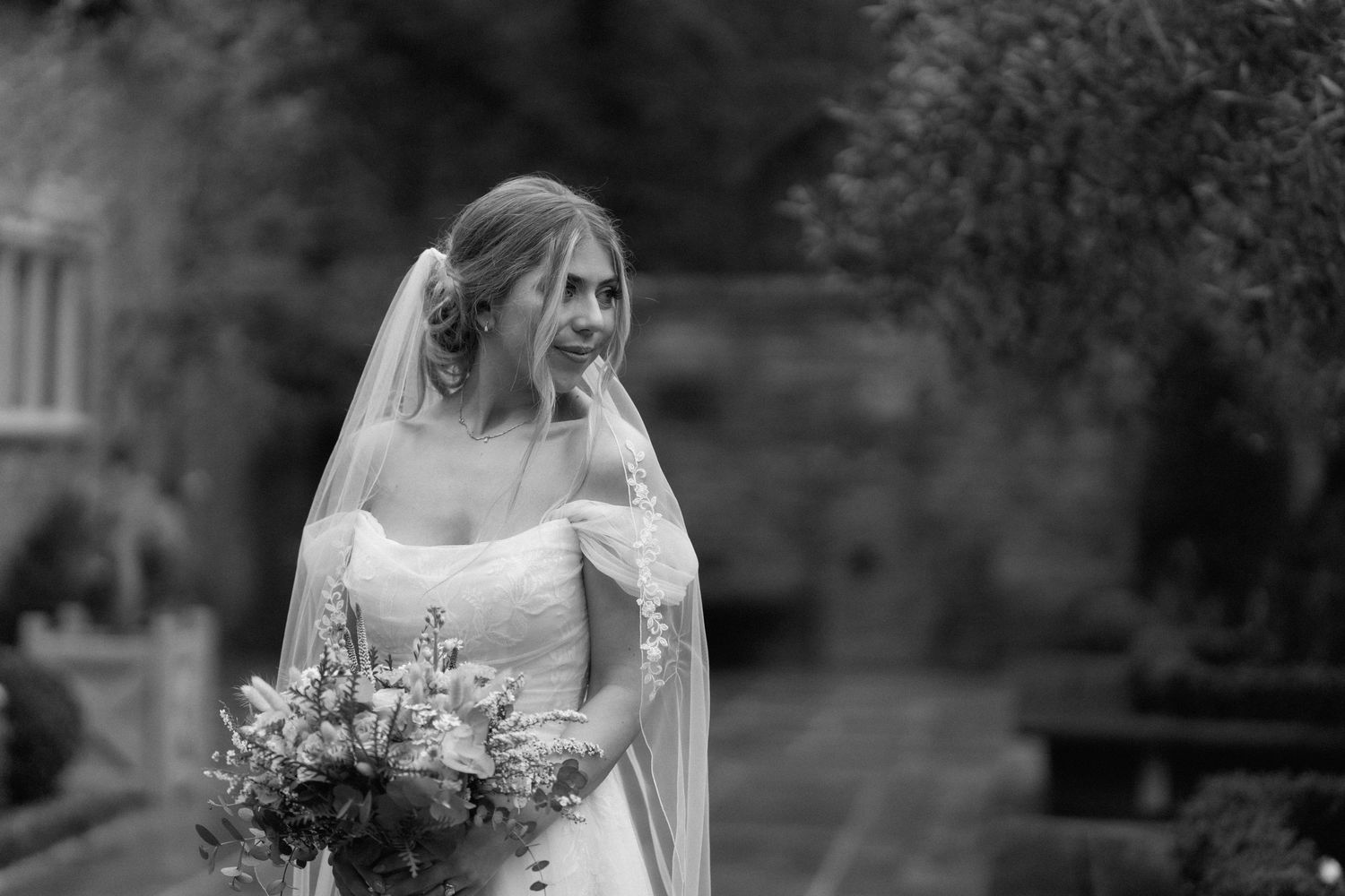 Black and white bridal portrait outdoors holding a lush floral bouquet at Shustoke Barn.