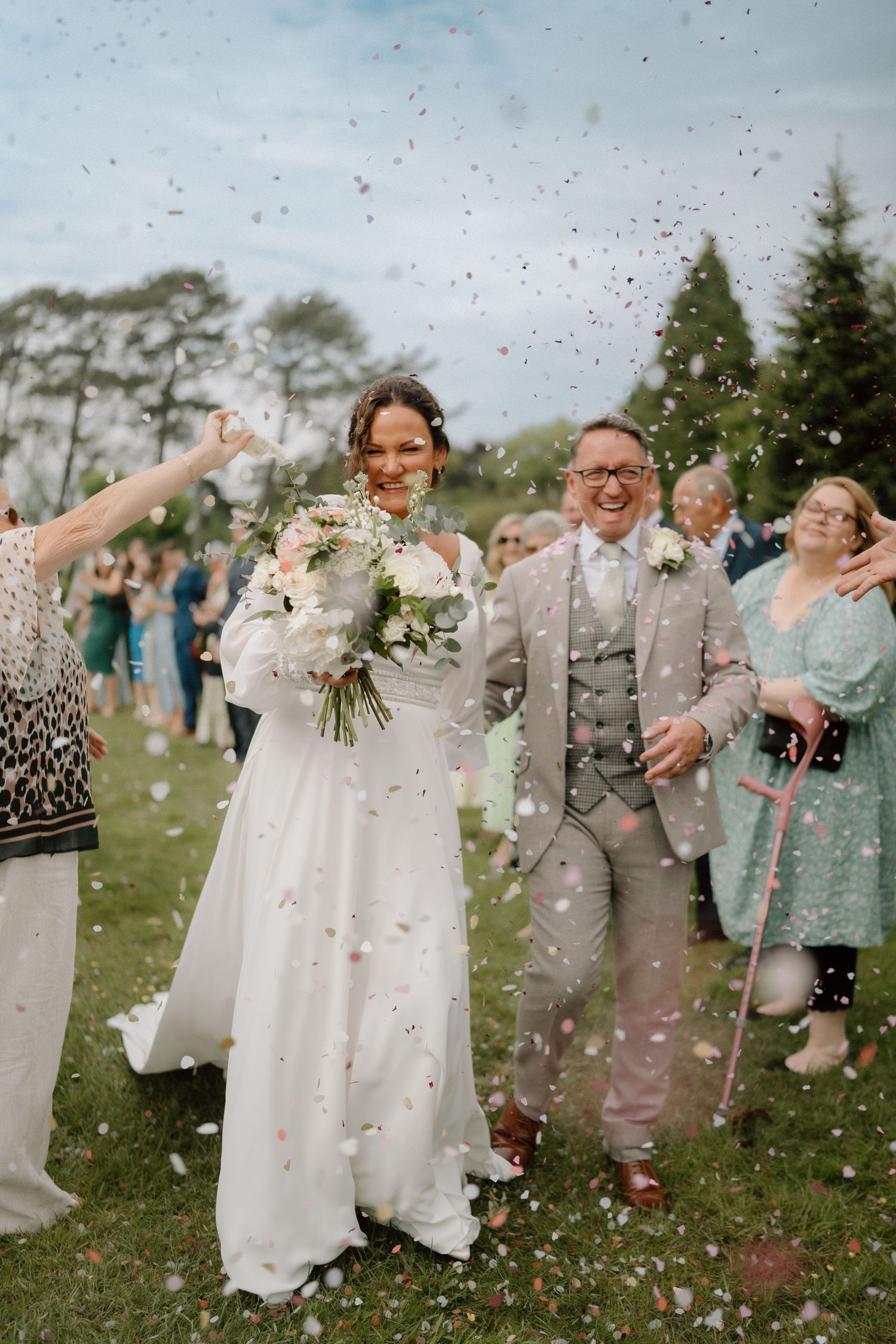 Wedding celebration on a lawn with confetti being thrown during a joyous moment at Nuthurst Grange.