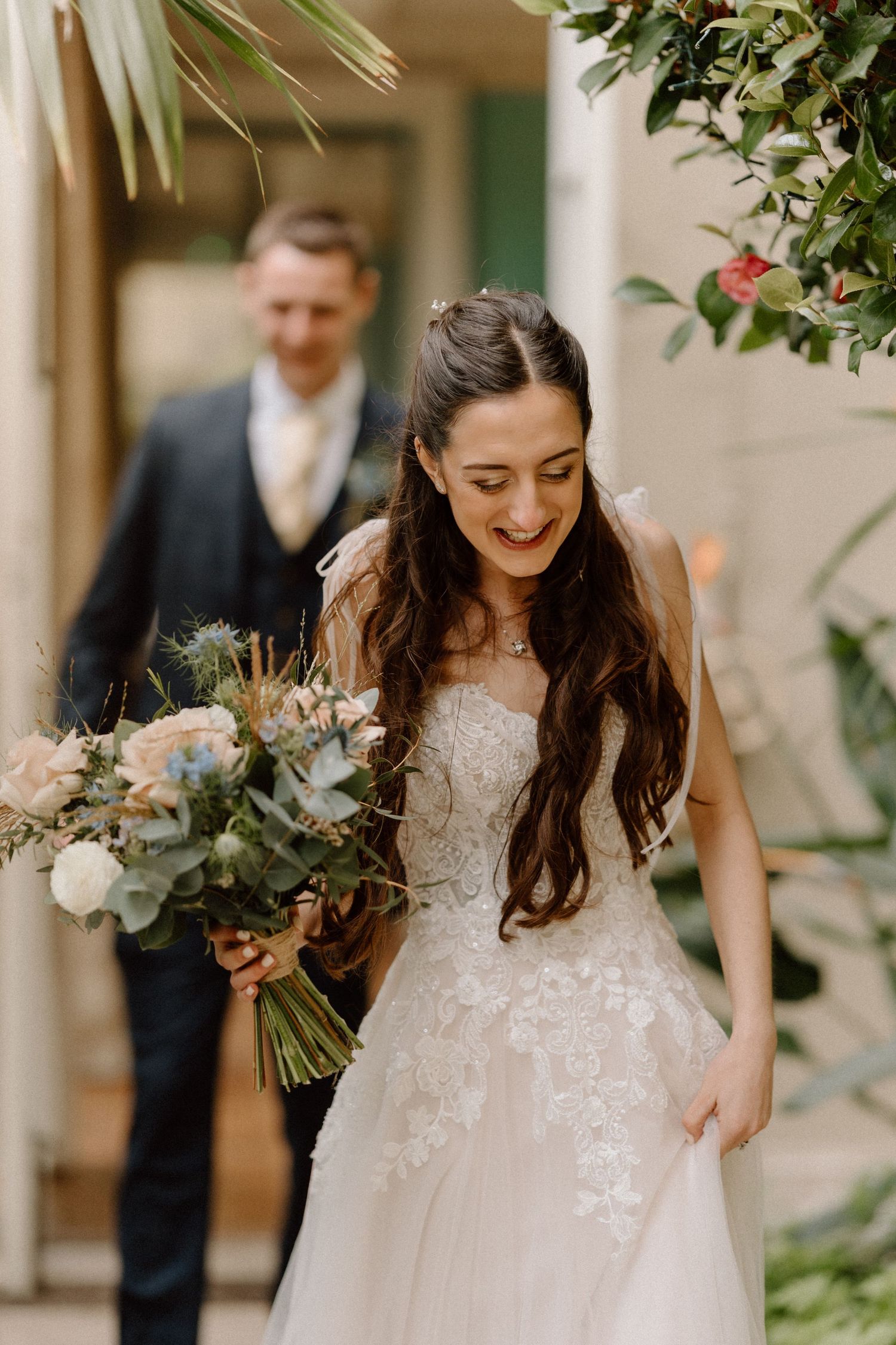 Joyful moment captured with bride holding bouquet in foreground at elegant venue at Prestwold Hall.