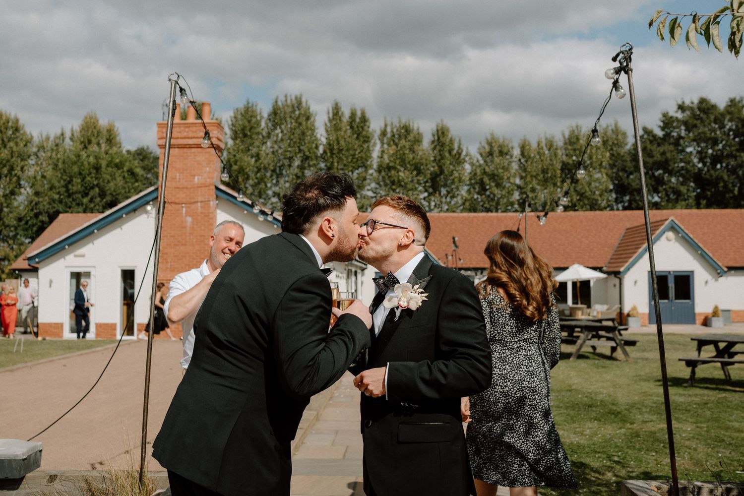 Outdoor wedding celebration at a countryside venue with rustic buildings in the background at The Manor House at Quorn.