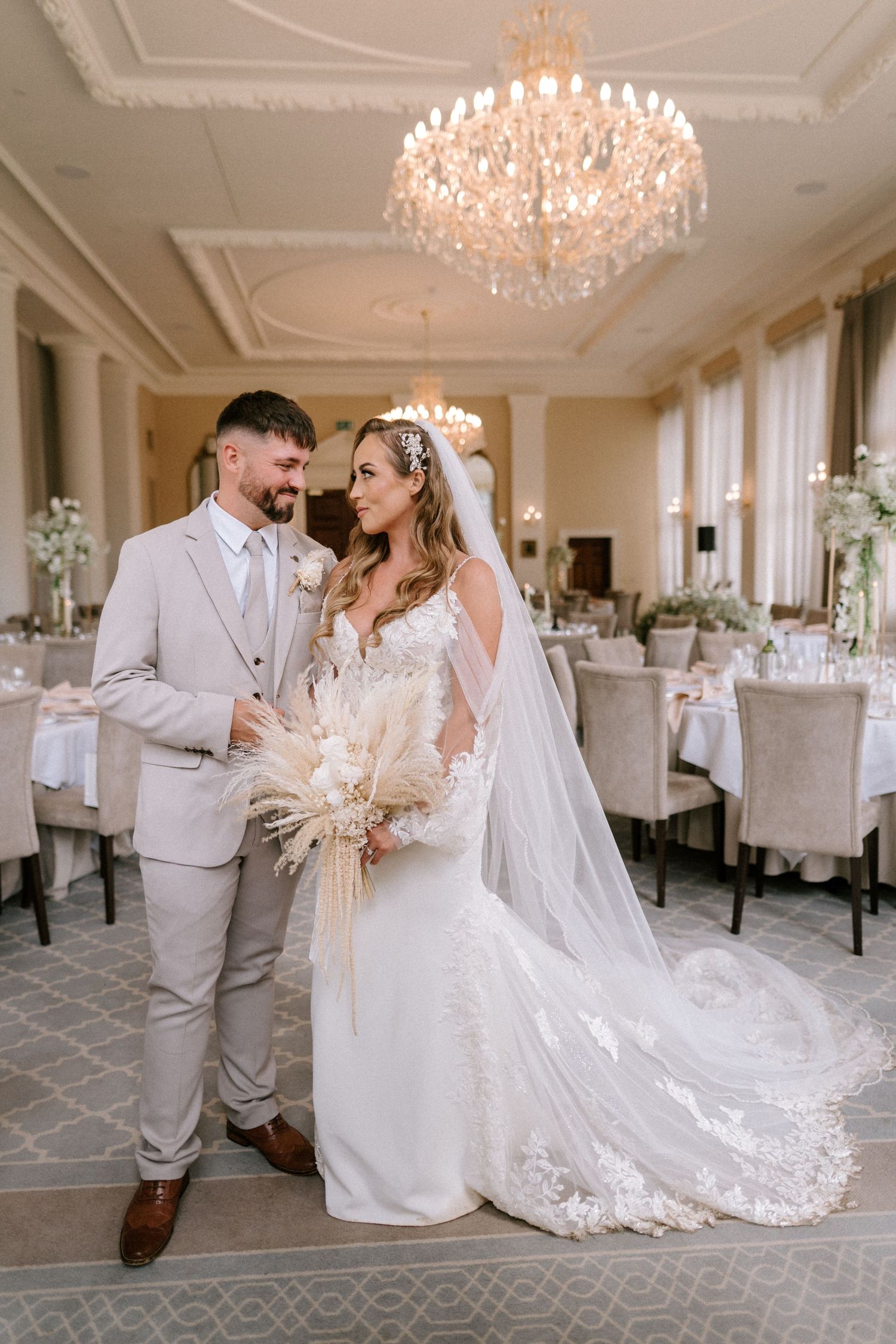 Elegant wedding reception room with crystal chandelier and classic table settings.
