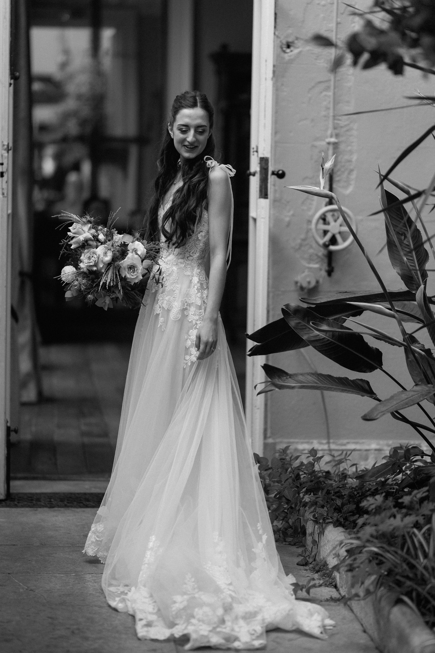 Black and white photo of a bride with long dark hair holding a bouquet in an elegant lace wedding dress at Prestwold Hall.