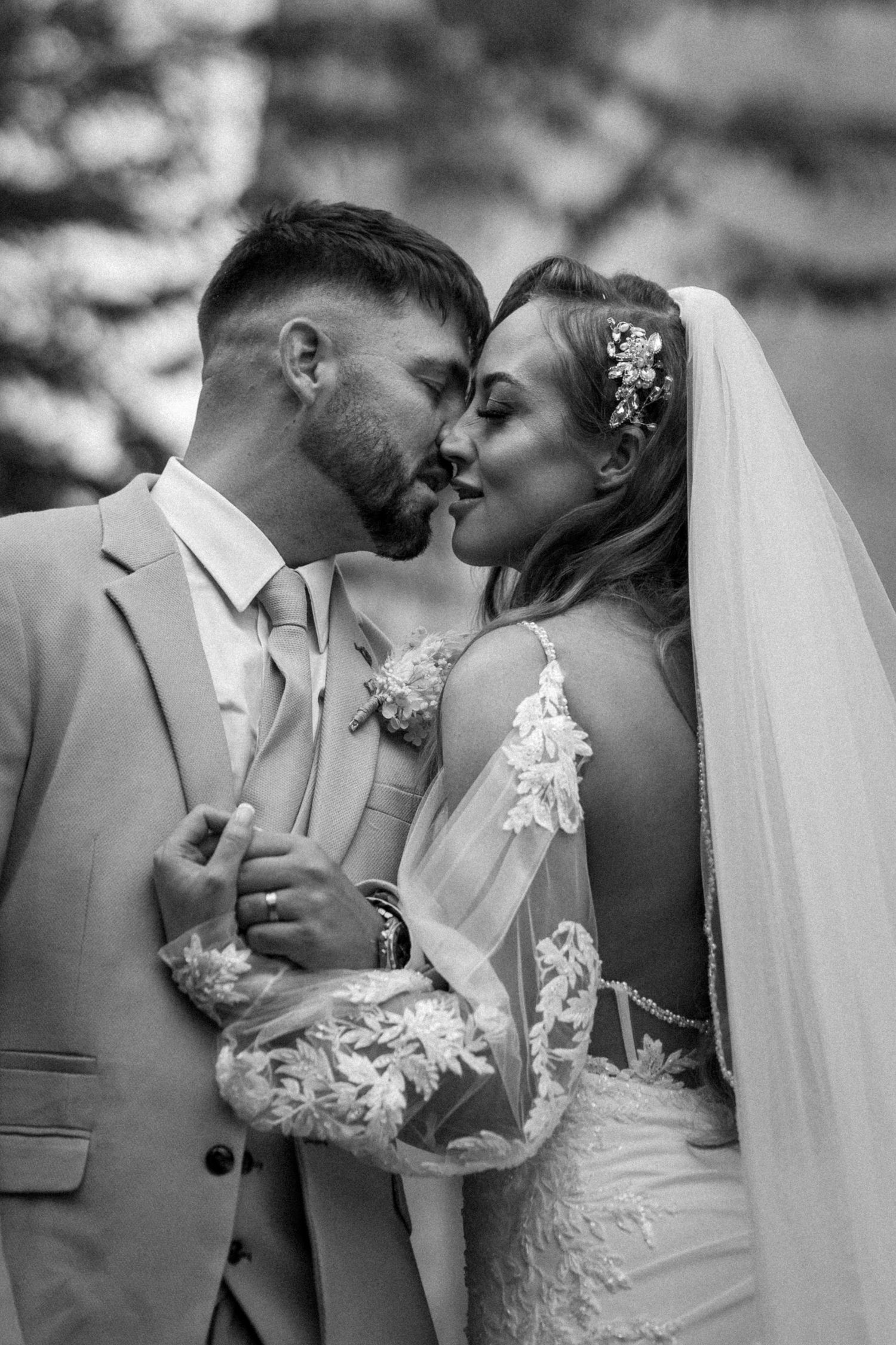 A romantic black and white portrait of a wedding couple sharing an intimate moment.