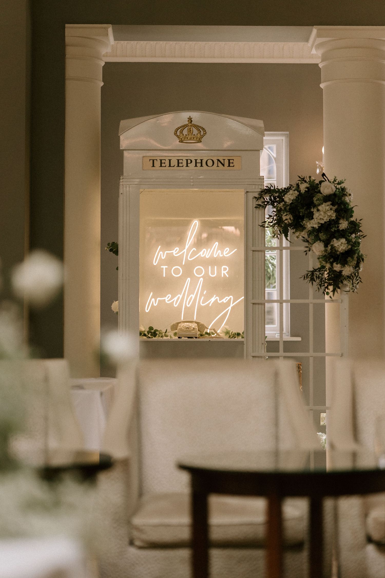 Elegant interior space with illuminated neon wedding welcome sign and classic white columns.