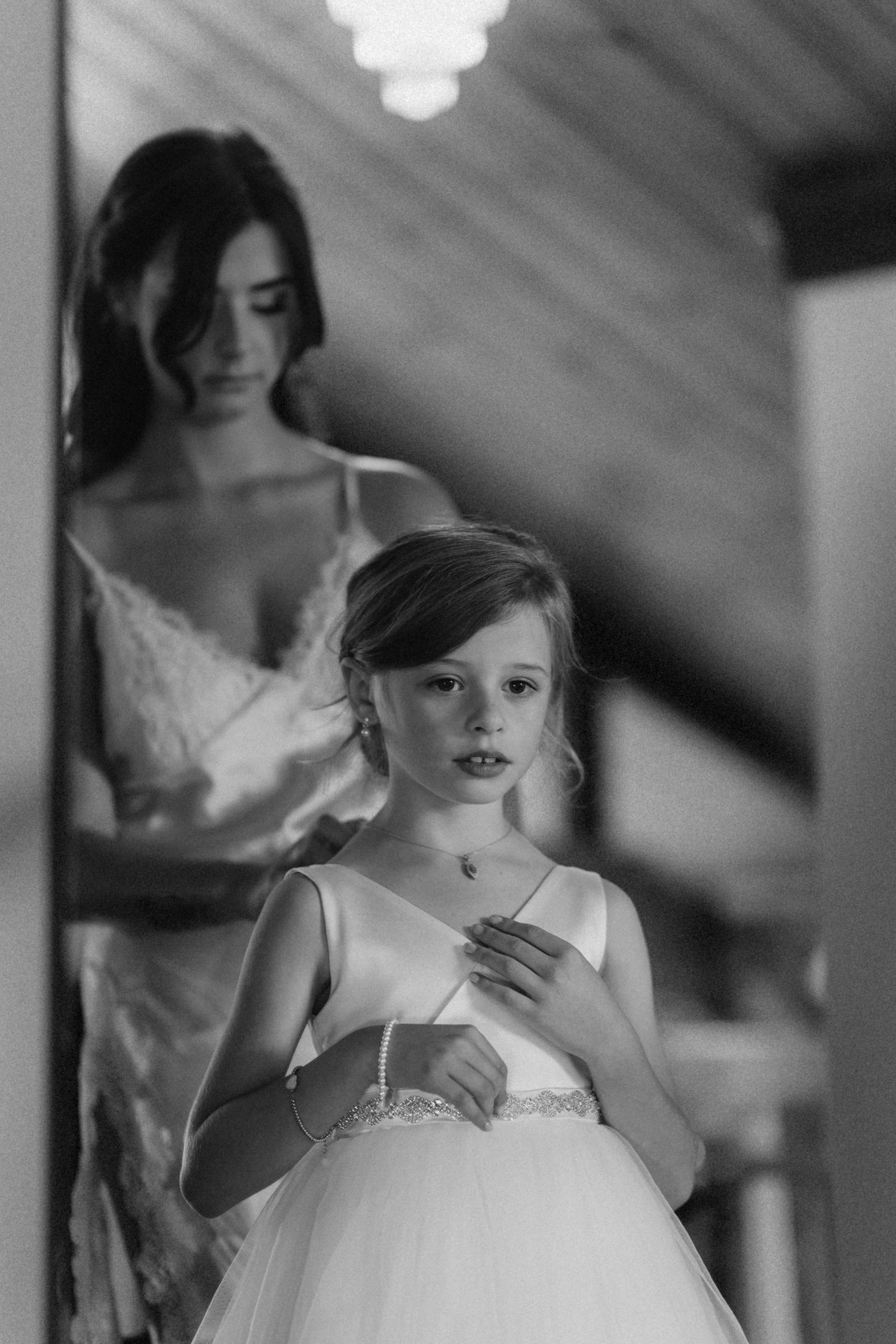 Black and white portrait of young attendant in white dress with sunbeams streaming through window.