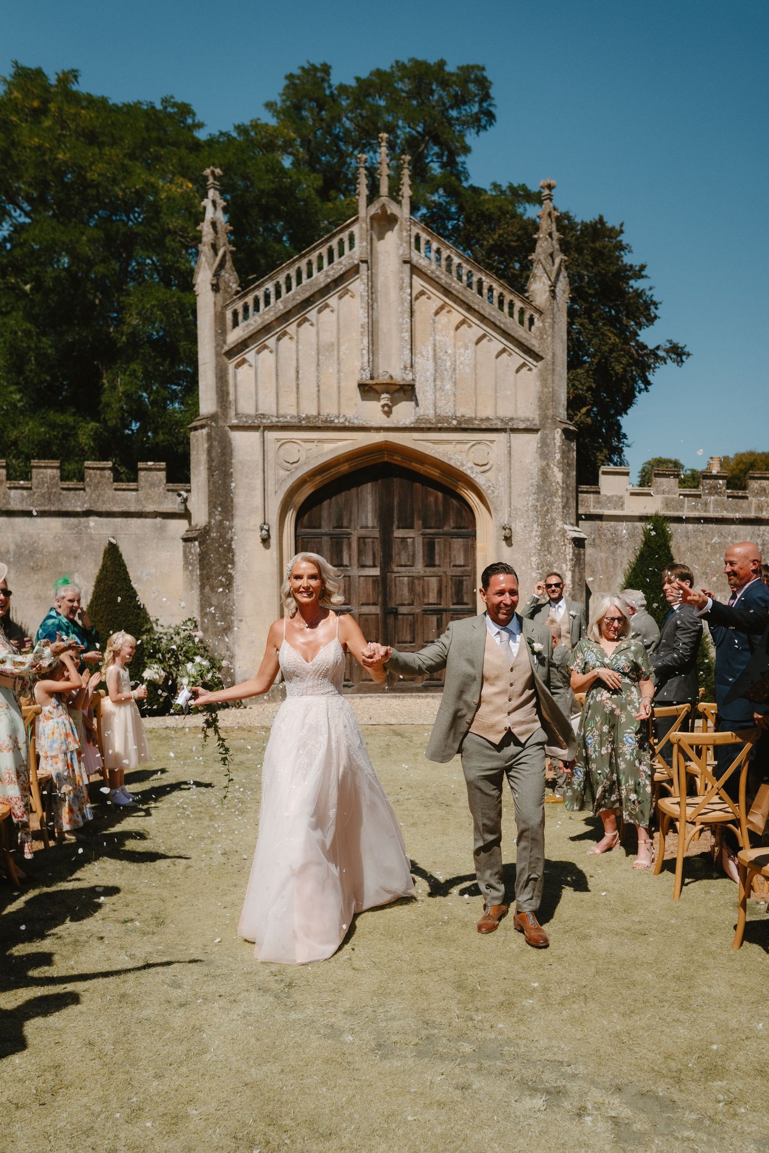 Newlyweds joyfully walk down the aisle after wedding ceremony at a historic castle venue.