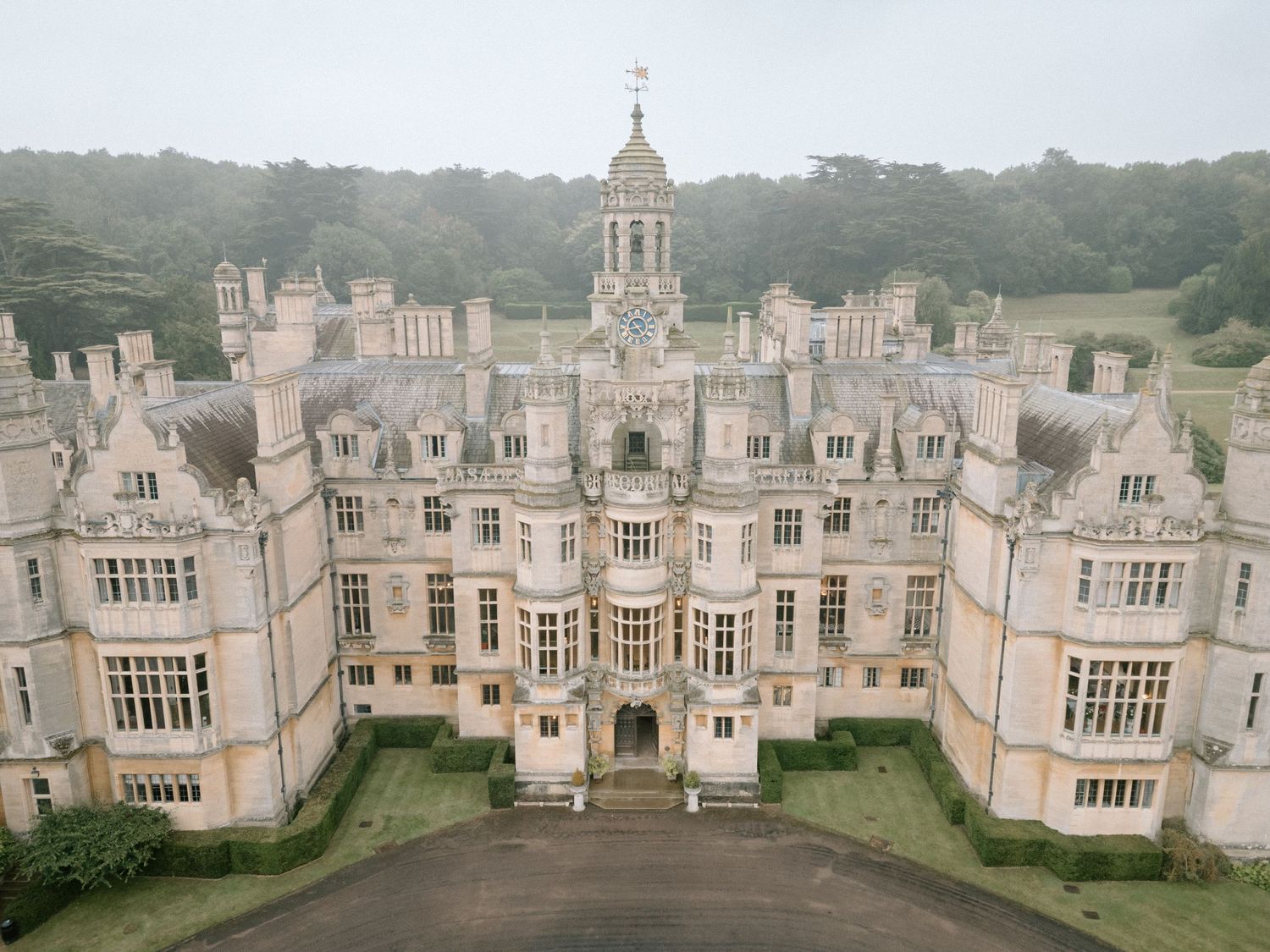 Symmetrical aerial view of an ornate English manor house with Tudor architecture and central tower at Harlaxton Manor.