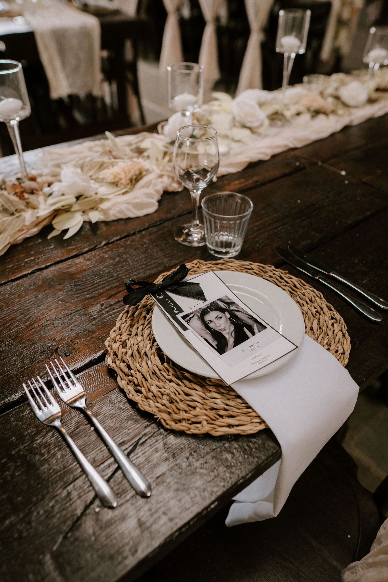 Rustic table setting with woven placemat, white napkin, and silver cutlery on weathered wooden surface.