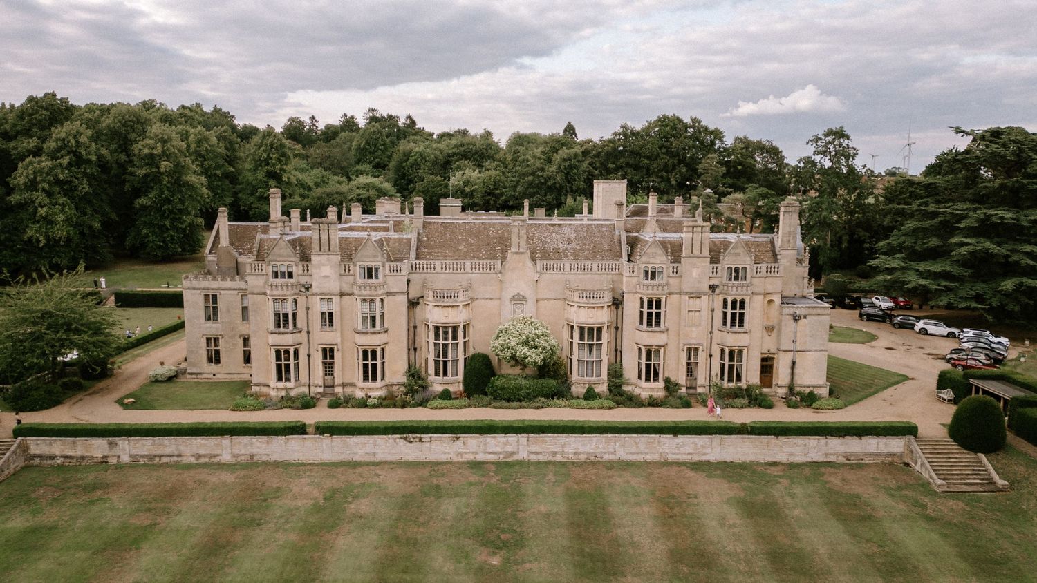 Aerial view of a majestic Gothic-style mansion with perfectly manicured grounds.