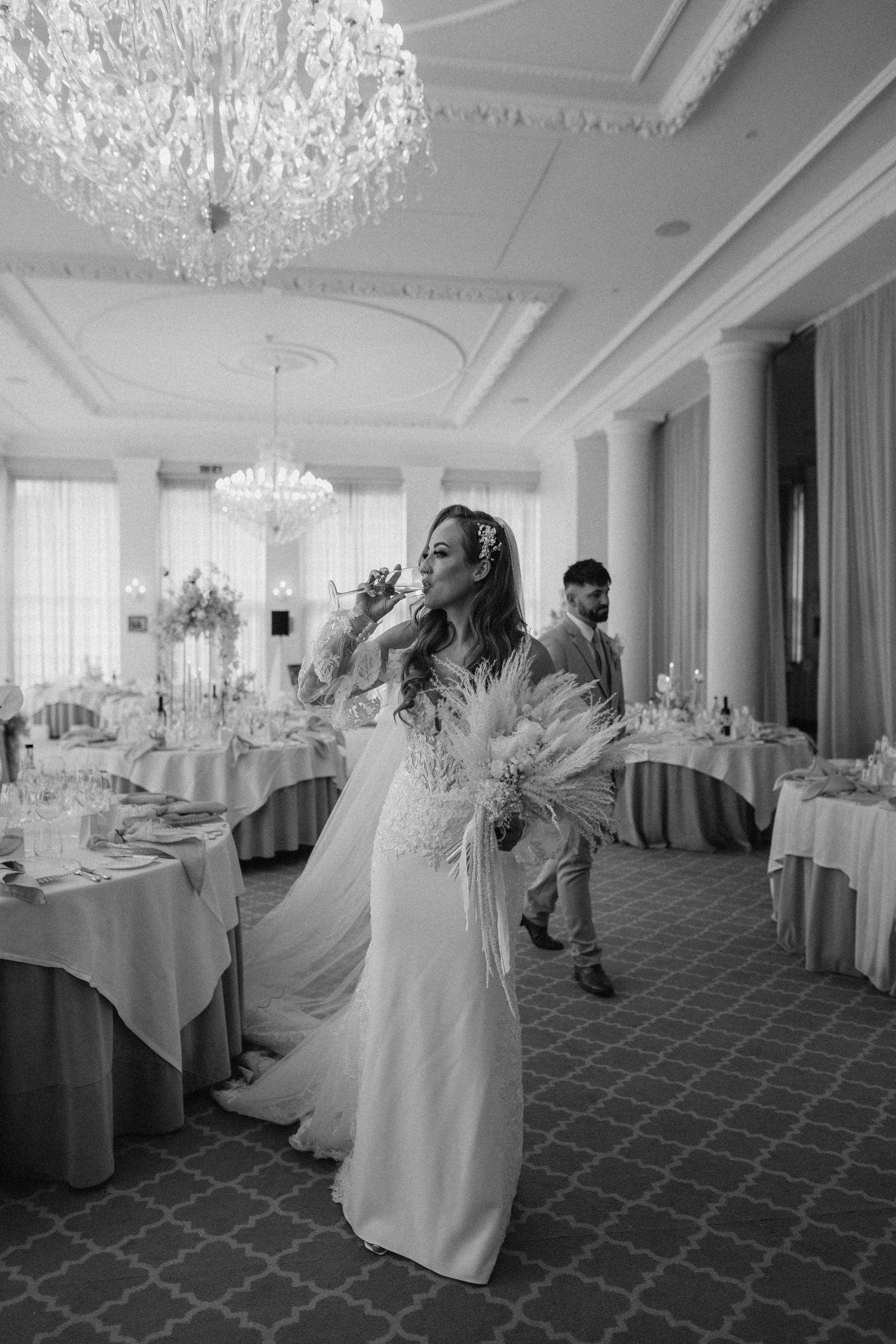 A joyful moment captured in an elegant reception hall with crystal chandeliers and round dining tables.