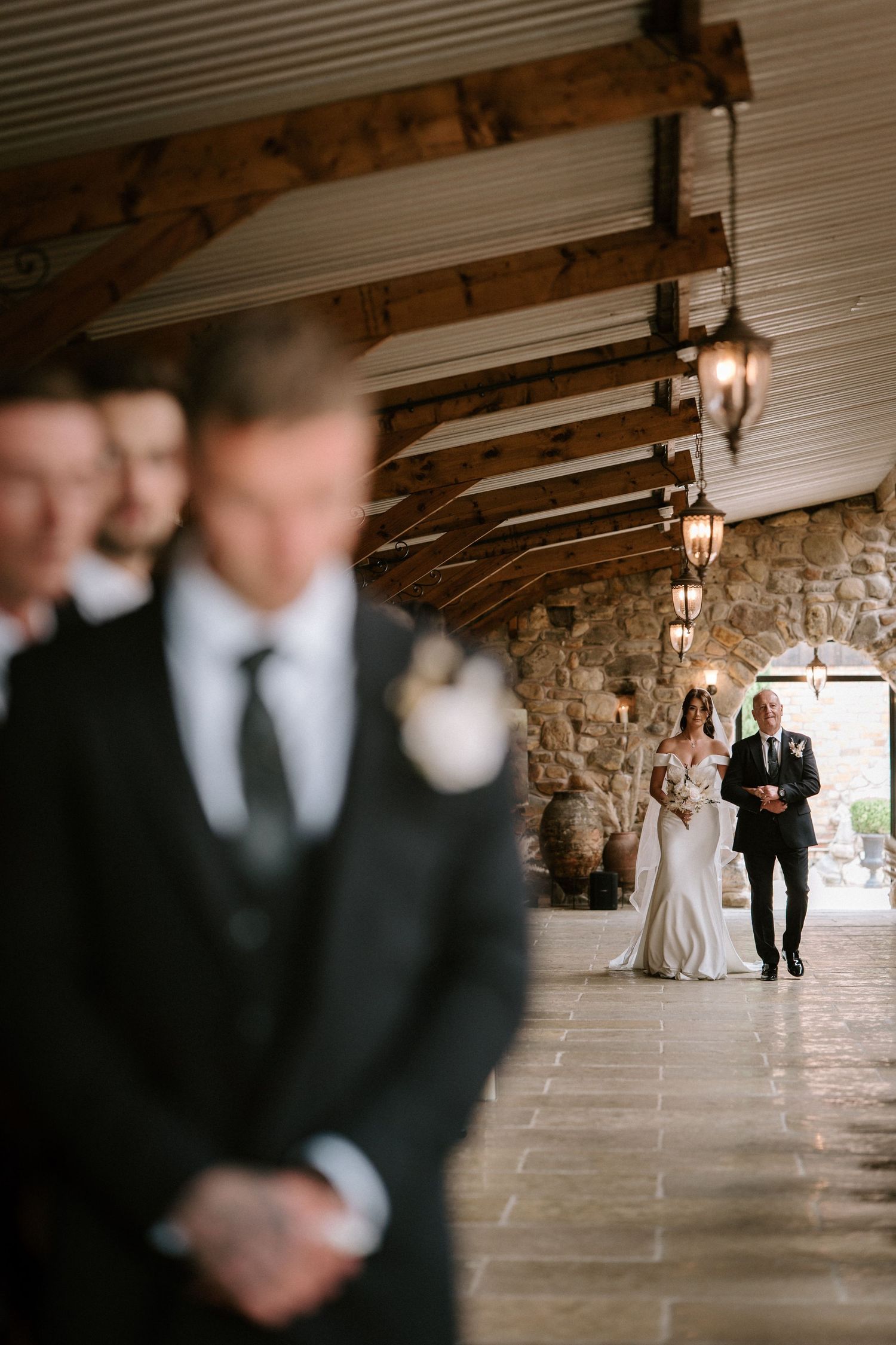 Atmospheric corridor shot with stone walls and wooden beams illuminated by hanging lanterns.
