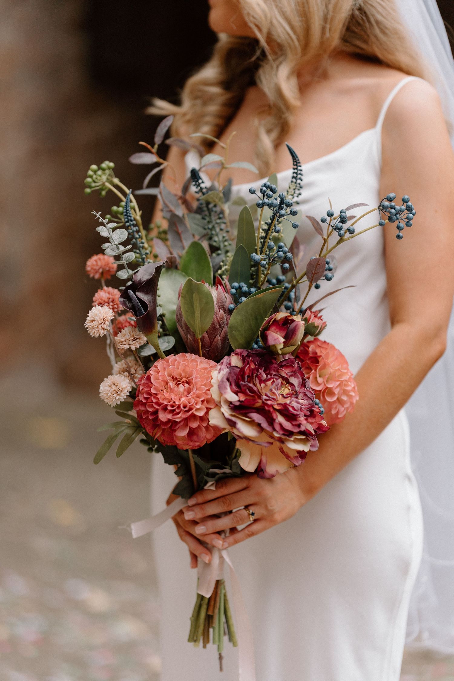 Close-up of a bridal bouquet featuring coral peonies, roses and wildflowers at Cheylesmore Manor in Coventry.